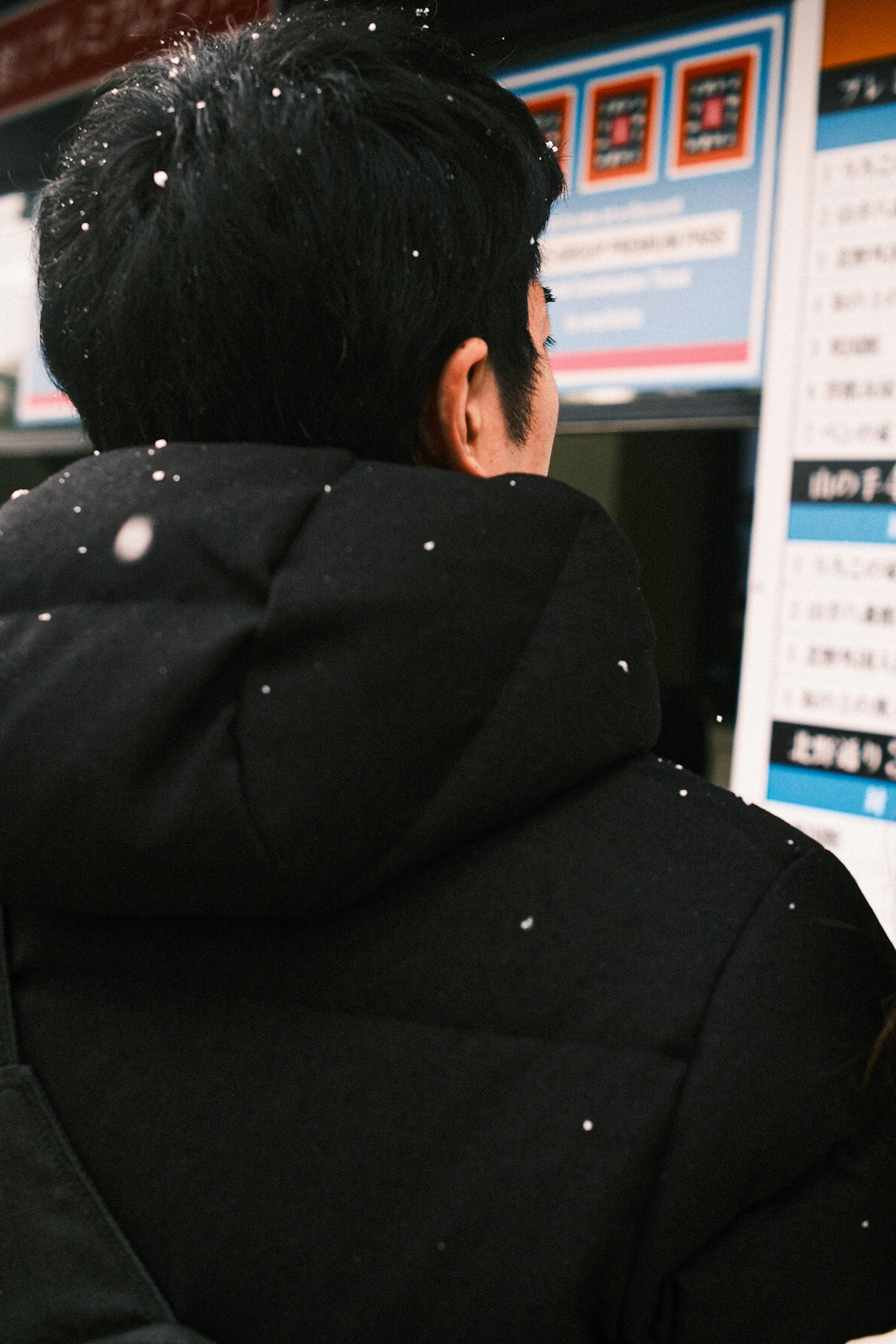 A man standing in front of a ticket machine in the snow