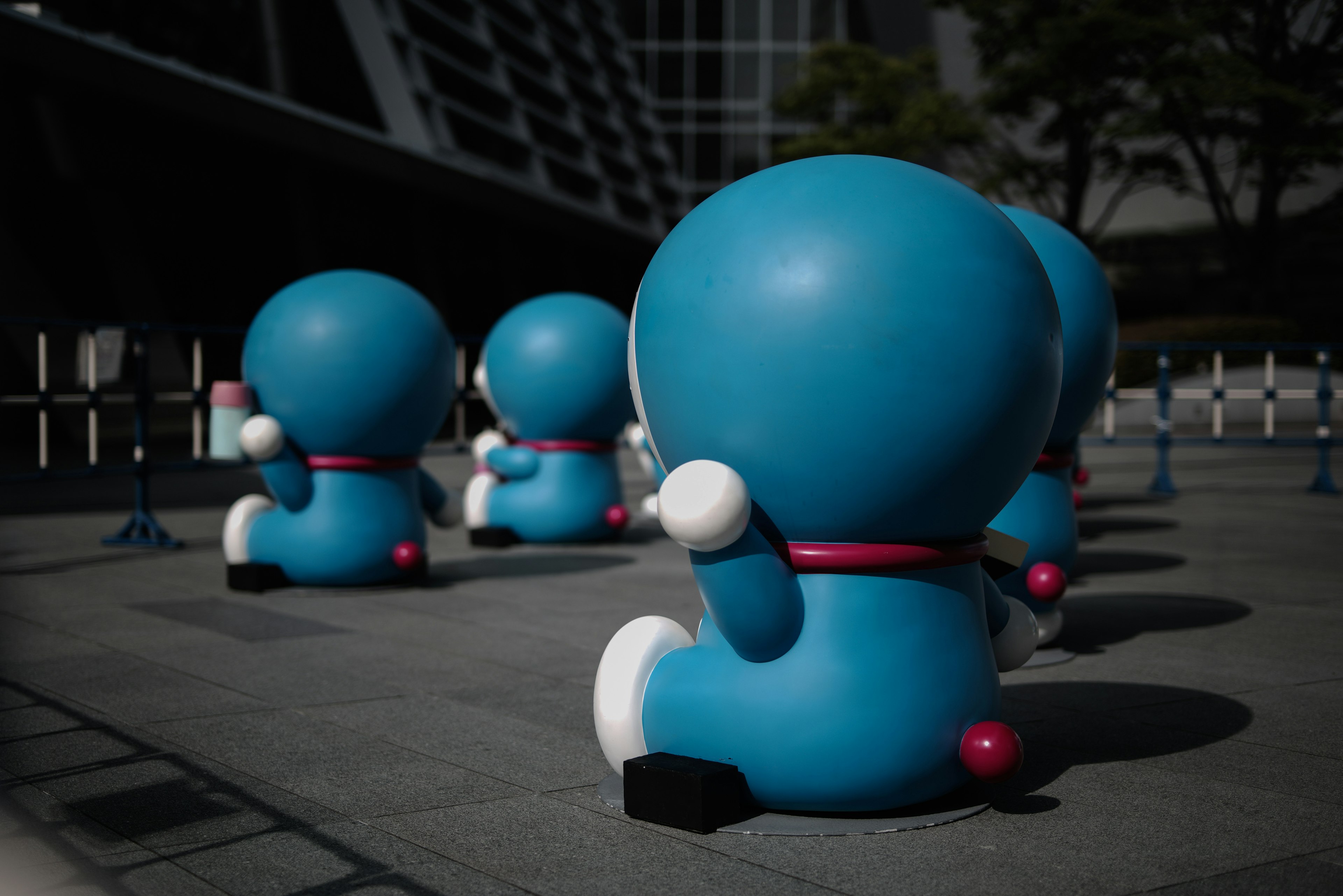 Blue robot characters facing away in a plaza setting