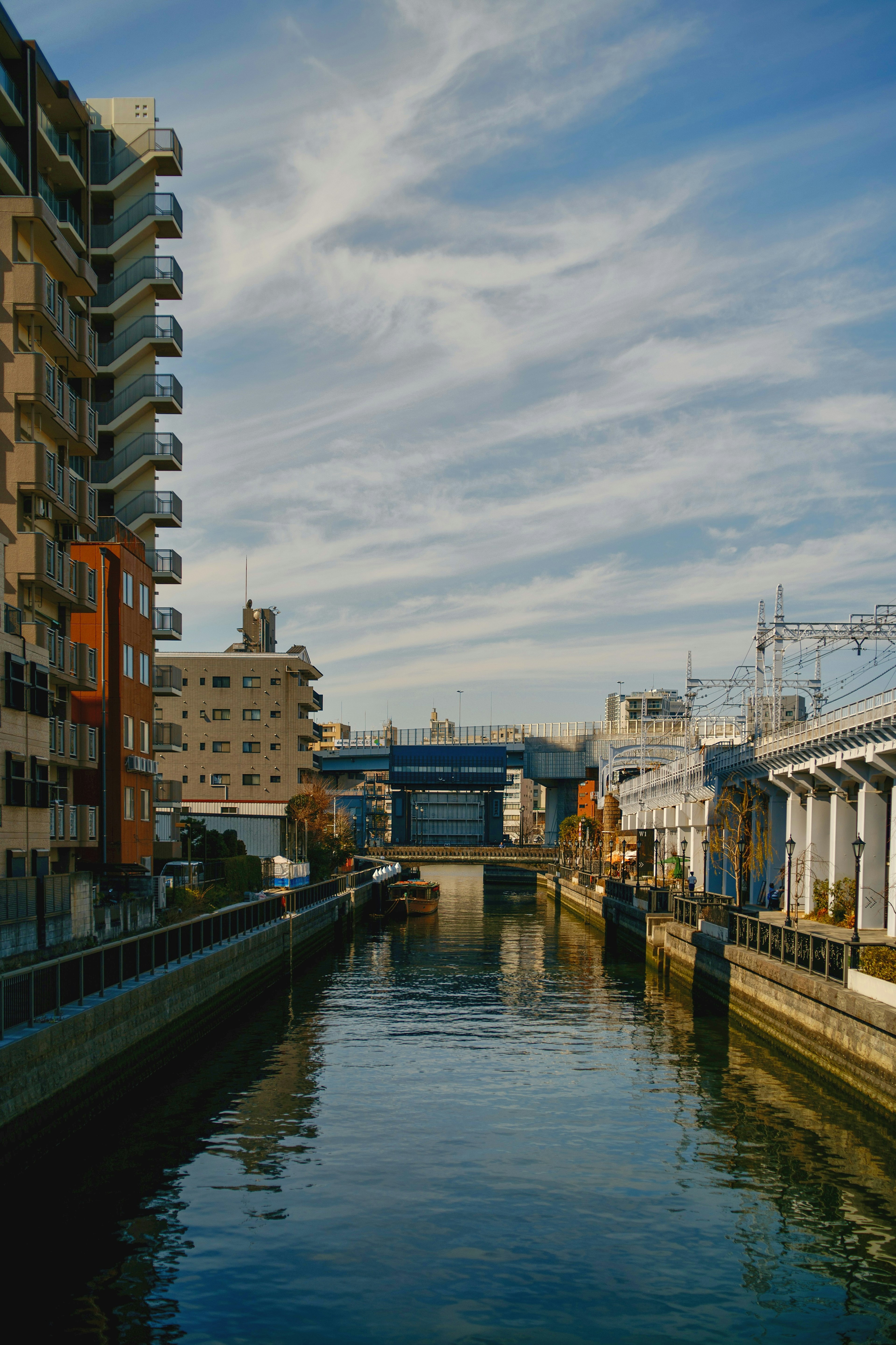 Cityscape with buildings along a calm river under a blue sky