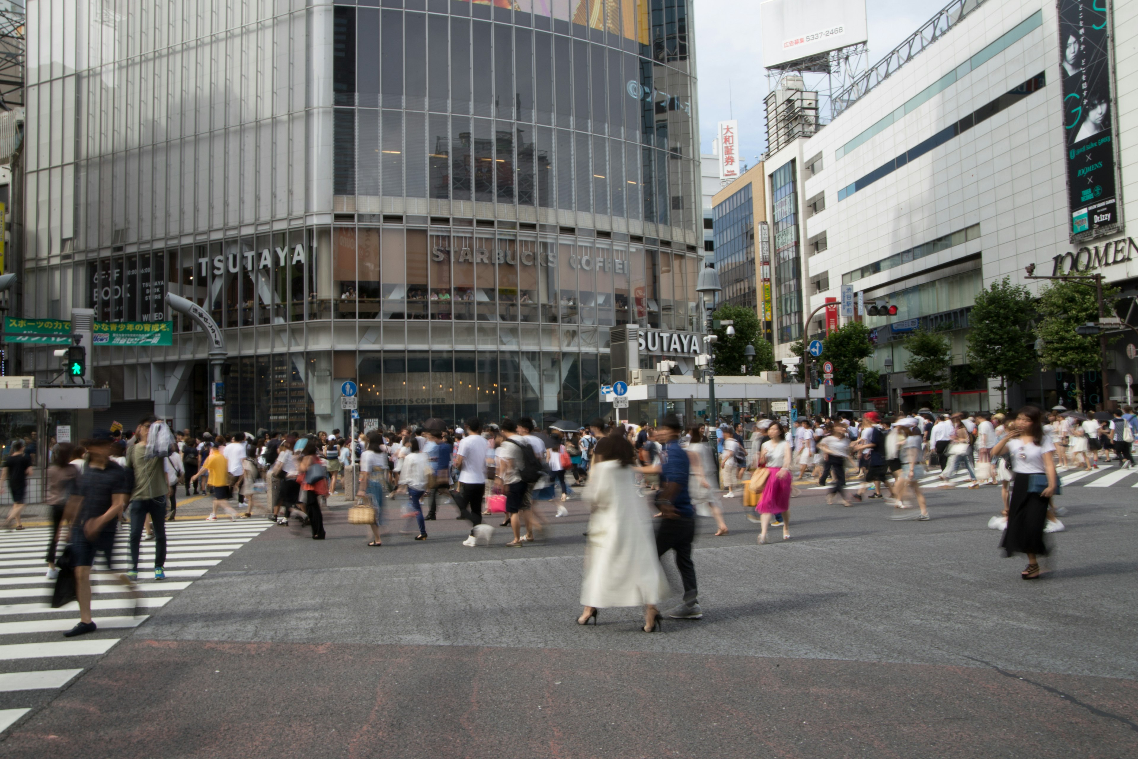 Menschenmenge, die die Shibuya-Kreuzung mit modernen Gebäuden überquert