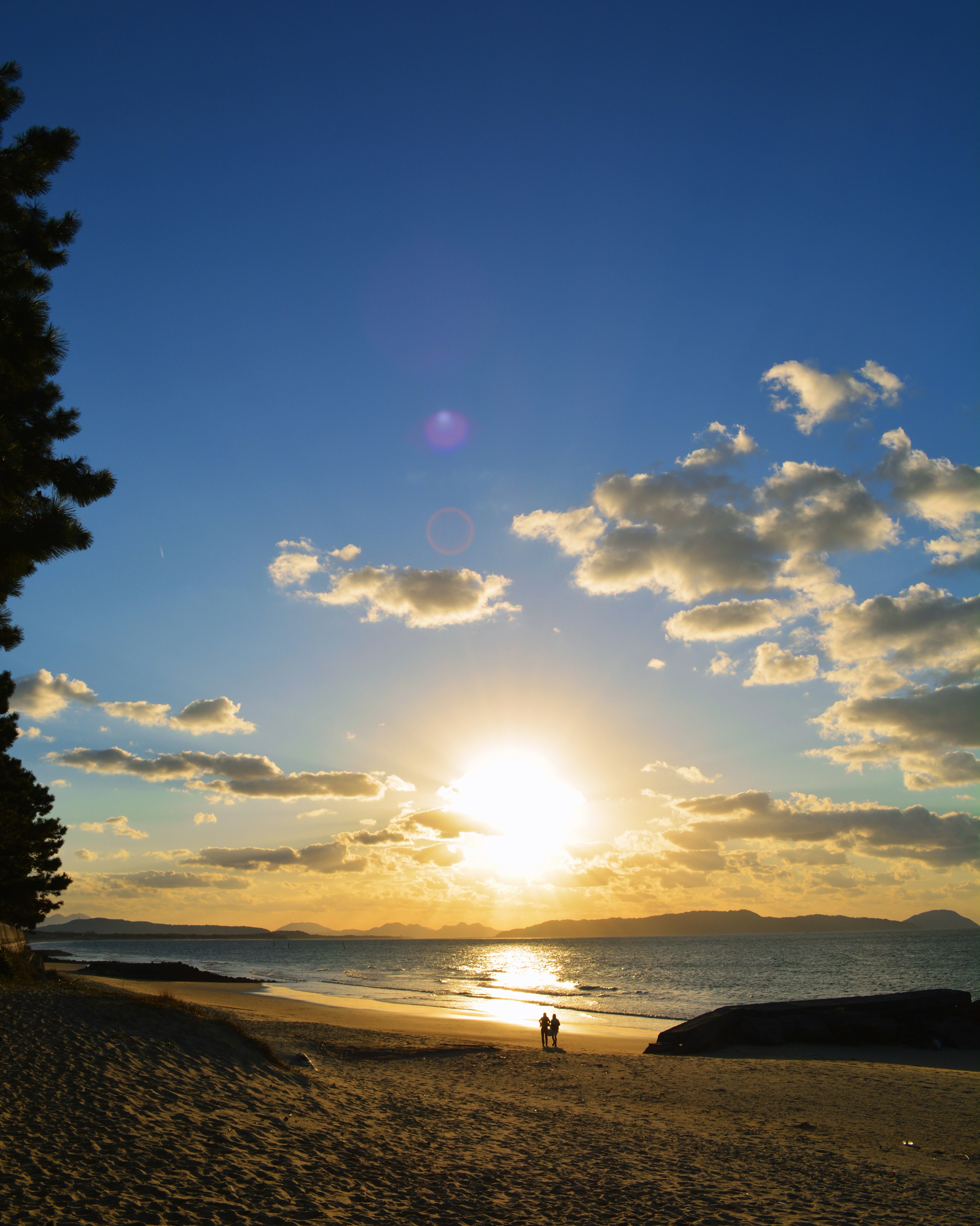 Scène de coucher de soleil sur la plage ciel bleu nuages blancs lumière du soleil se reflétant sur la mer