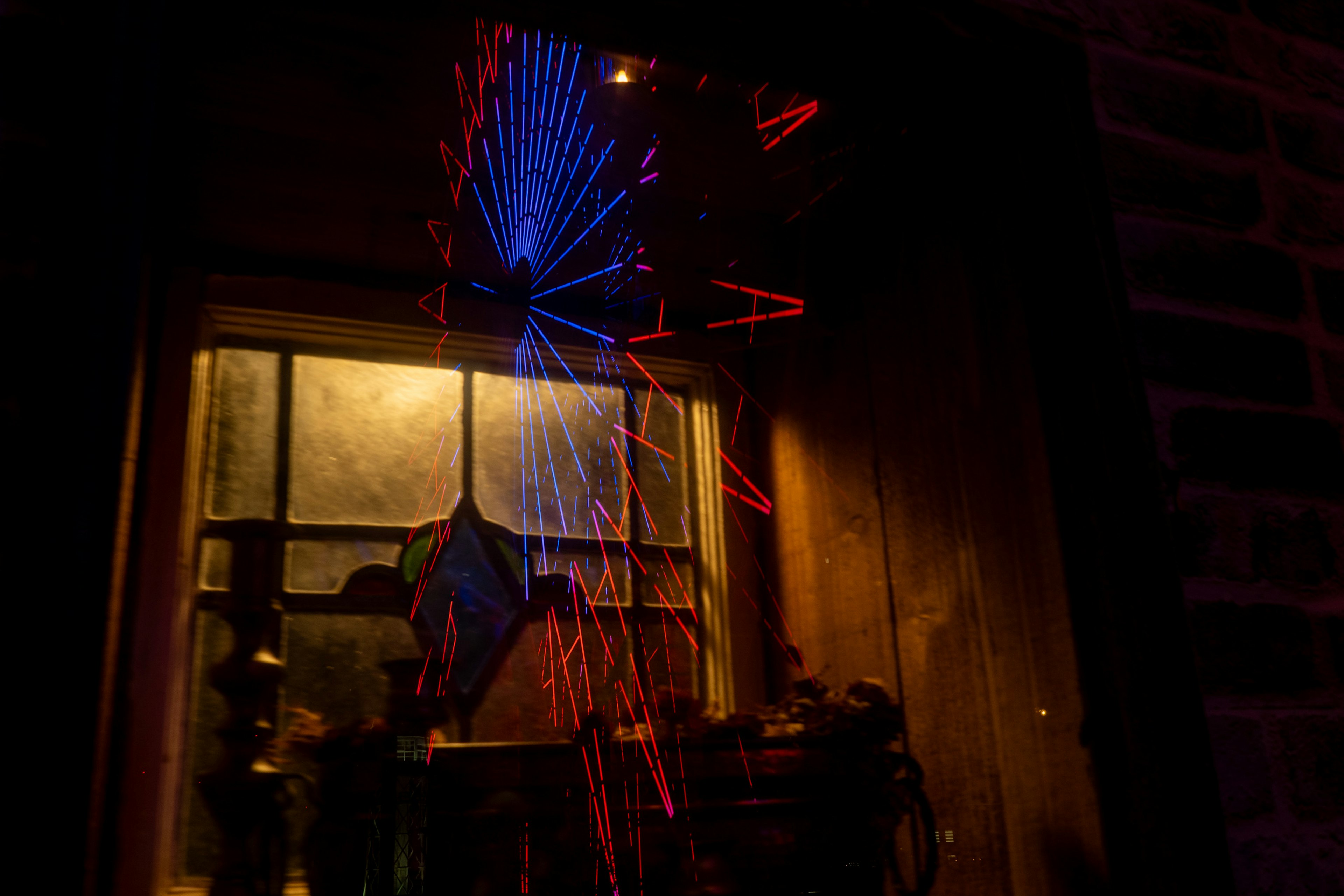 Scène nocturne avec des faisceaux de lumière rouge et bleue émanant d'une fenêtre