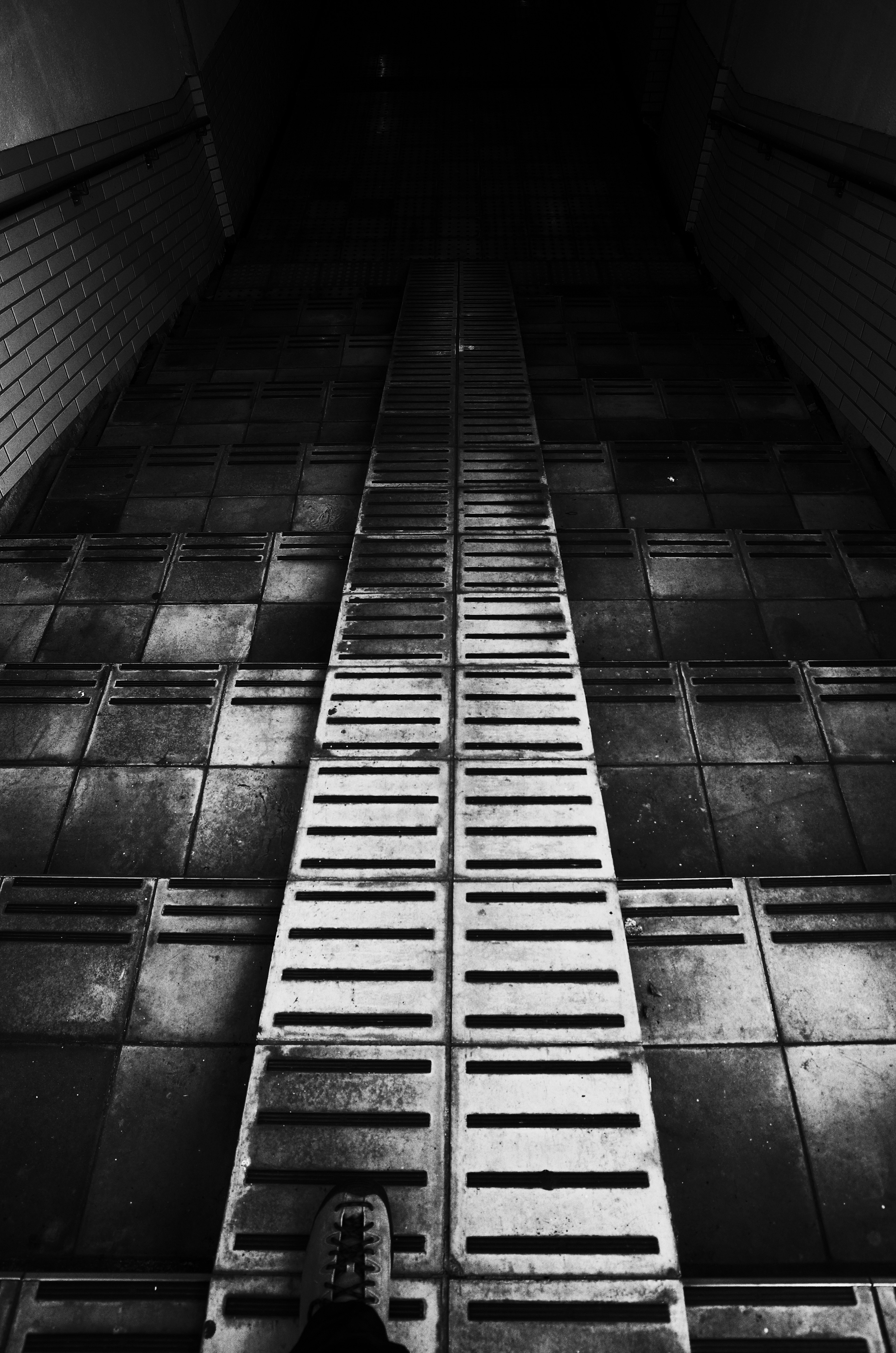 A dark corridor with metal grating and tiled floor