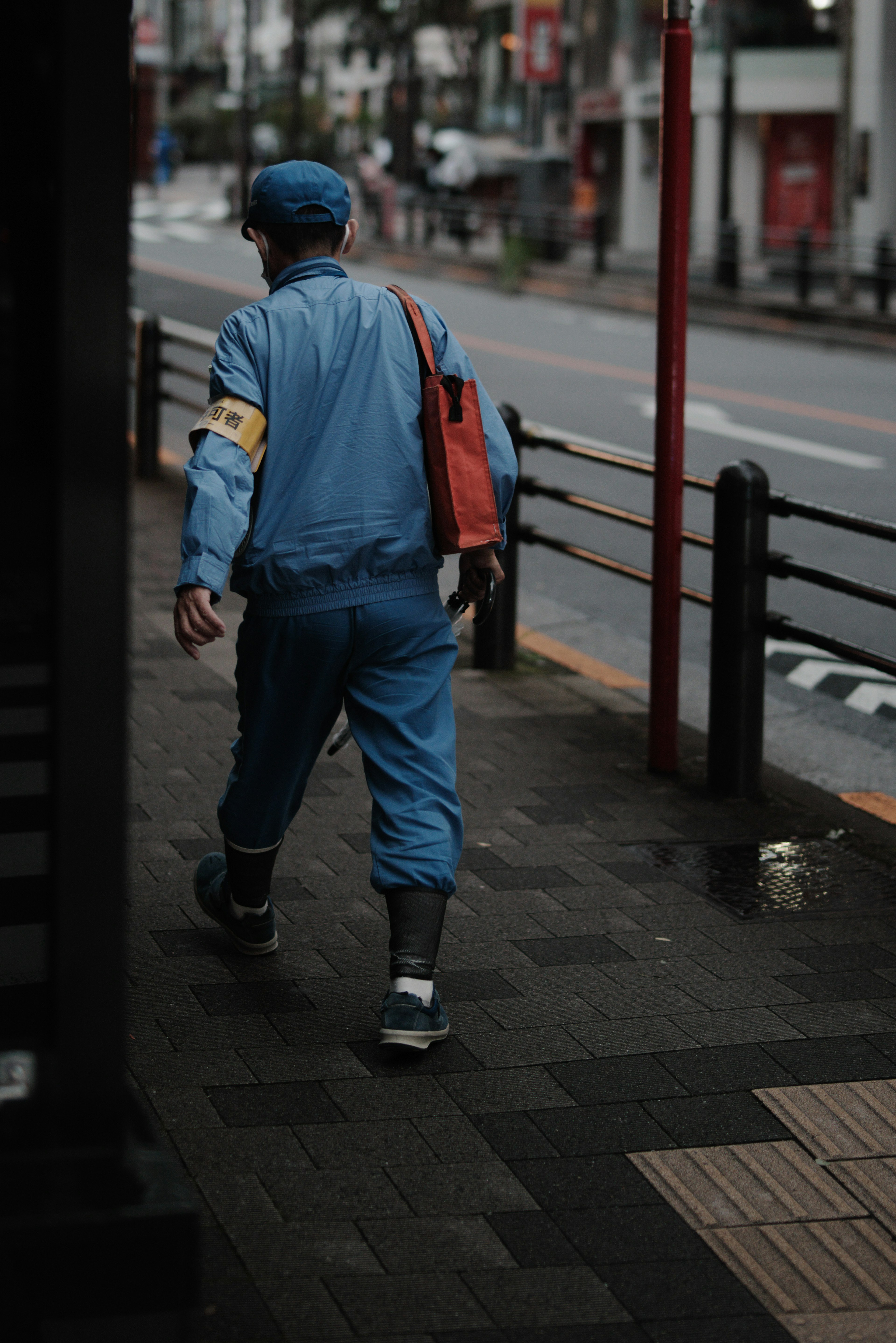 A worker in a blue uniform walking down the street