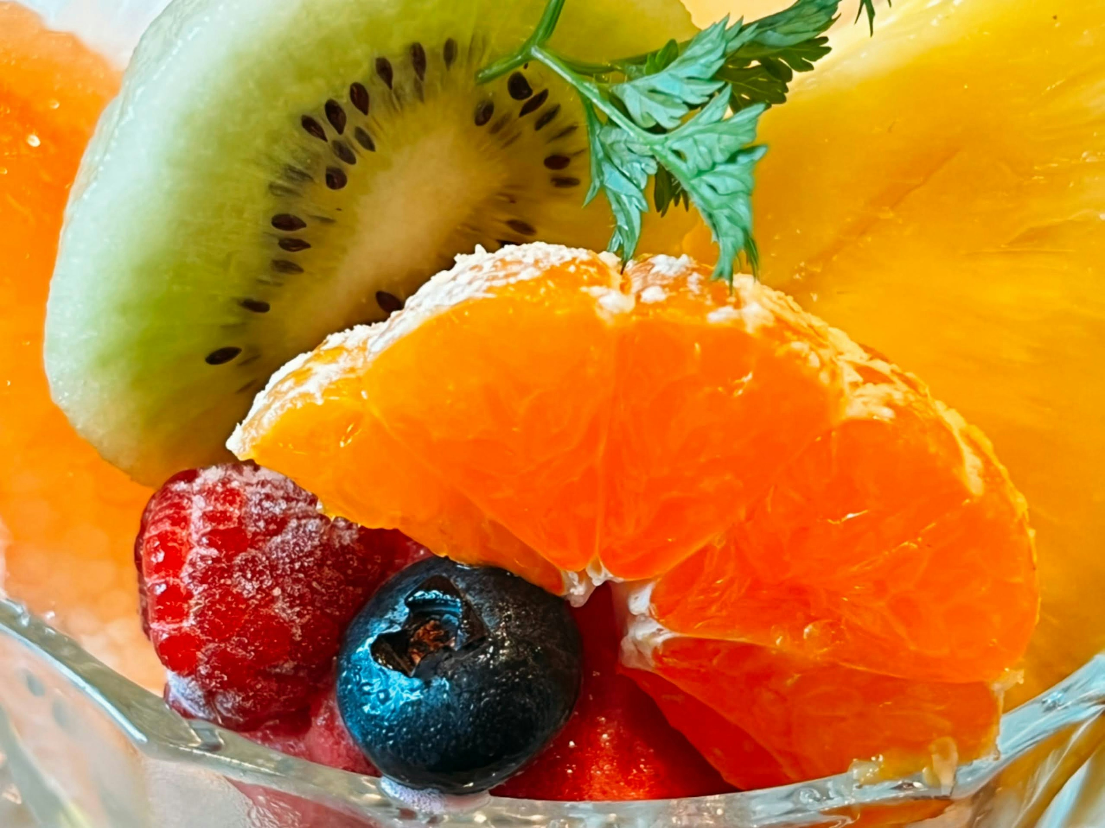 Colorful fruit salad bowl featuring kiwi, orange, pineapple, raspberry, and blueberry