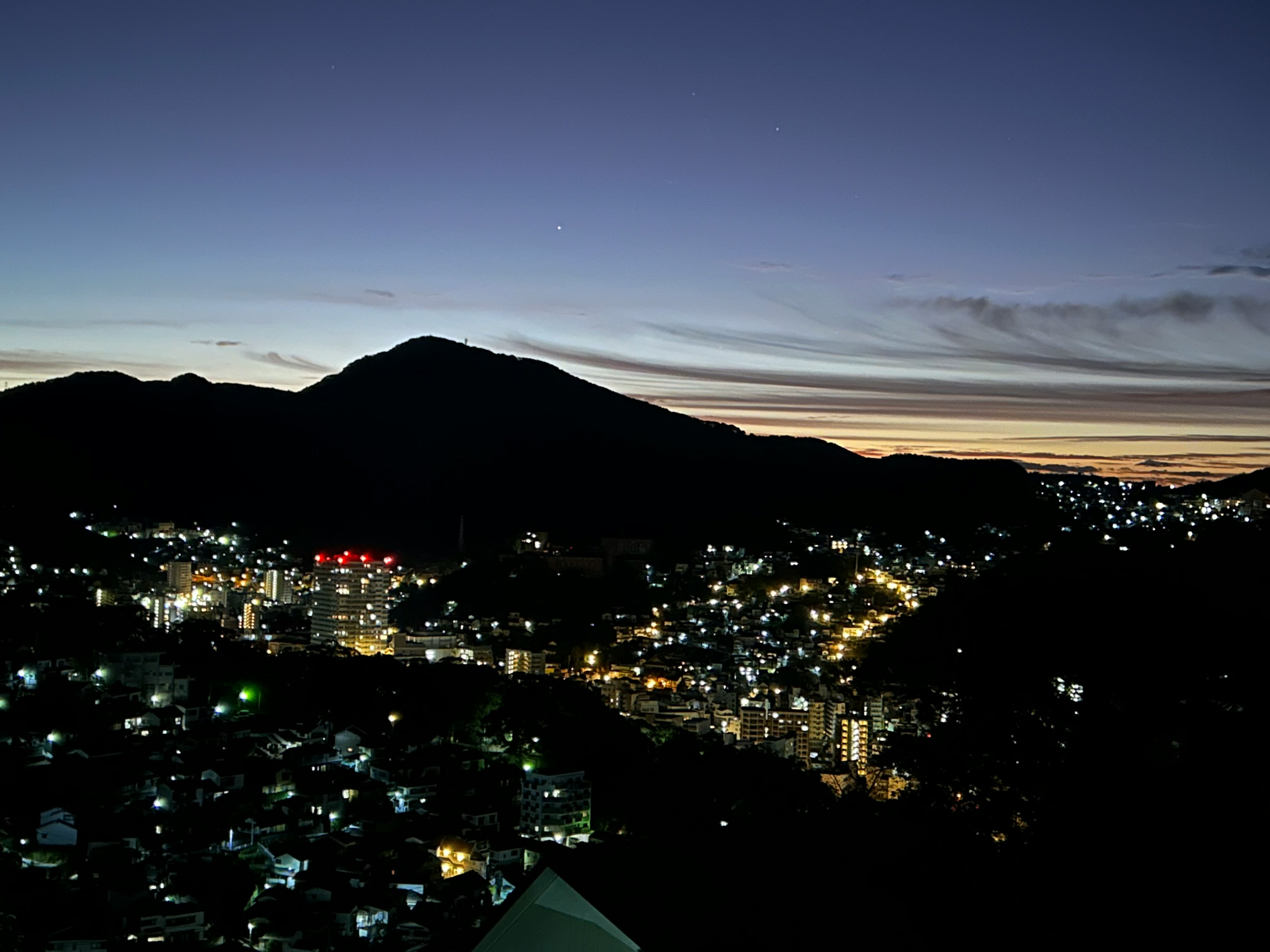 Vista crepuscular de montañas y luces de la ciudad brillantes