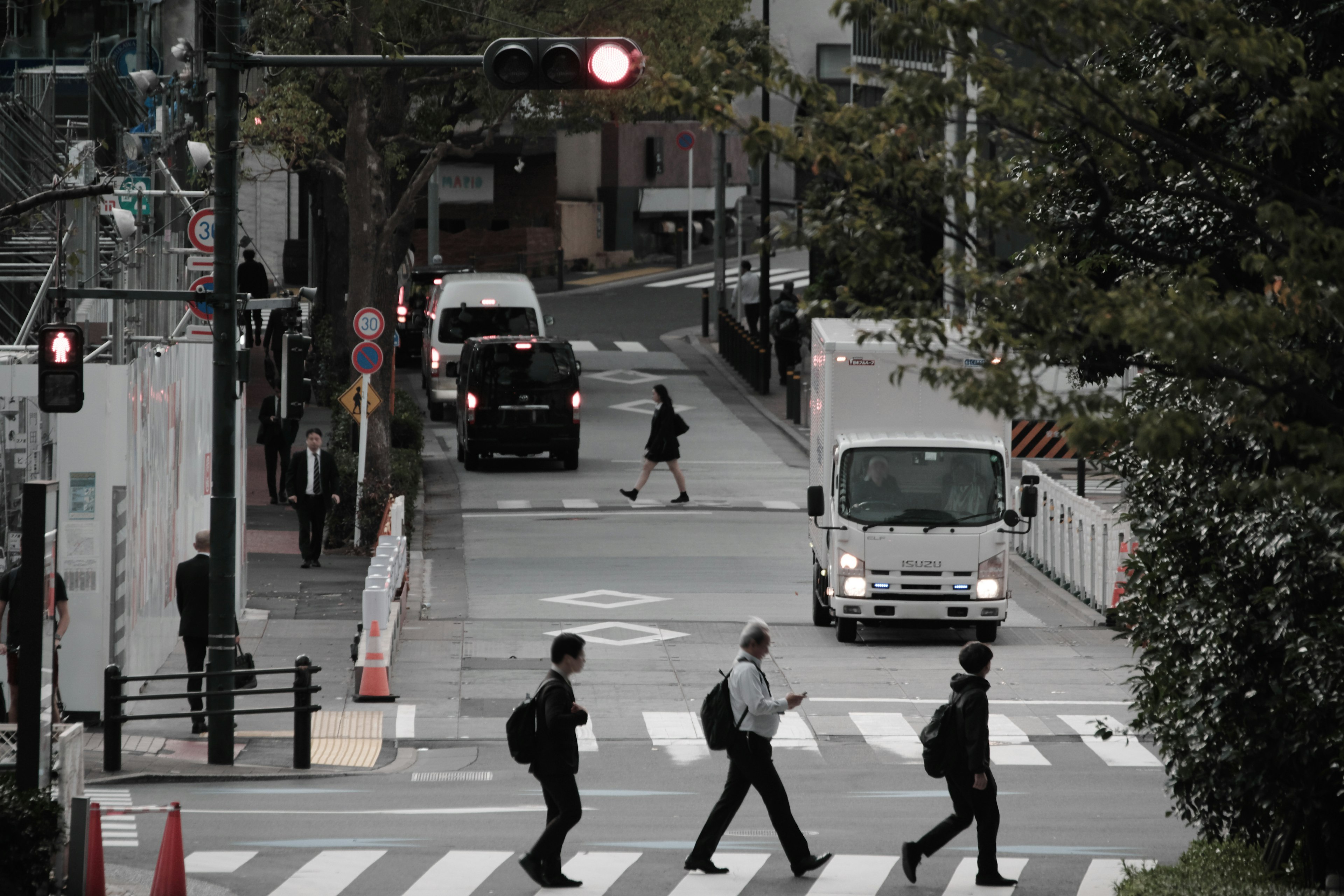 赤信号の交差点を渡る人々と車