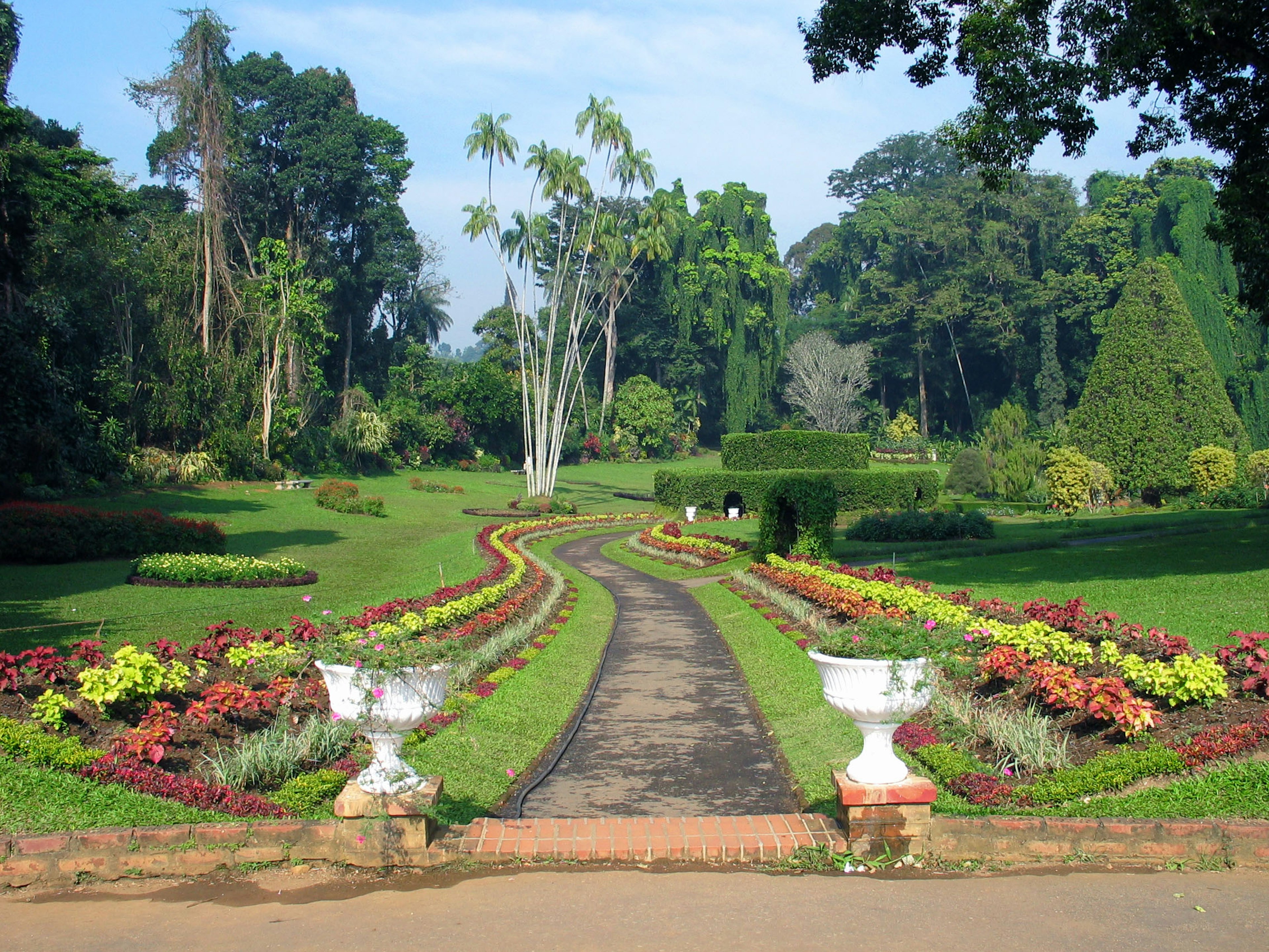 Üppiger Gartenweg gesäumt von bunten Blumenbeeten und Bäumen