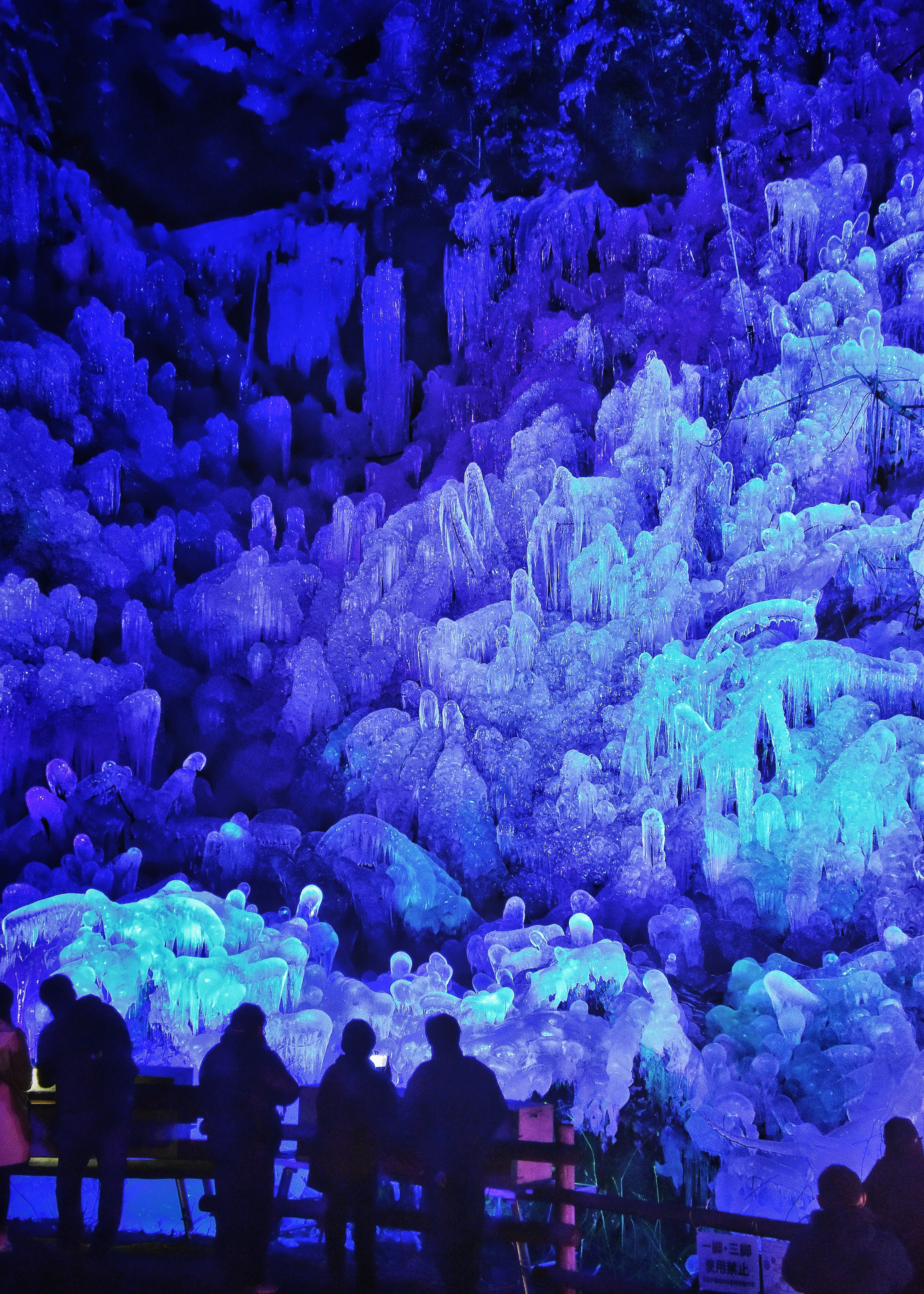 Silhouette di persone in una grotta di ghiaccio blu con stalattiti