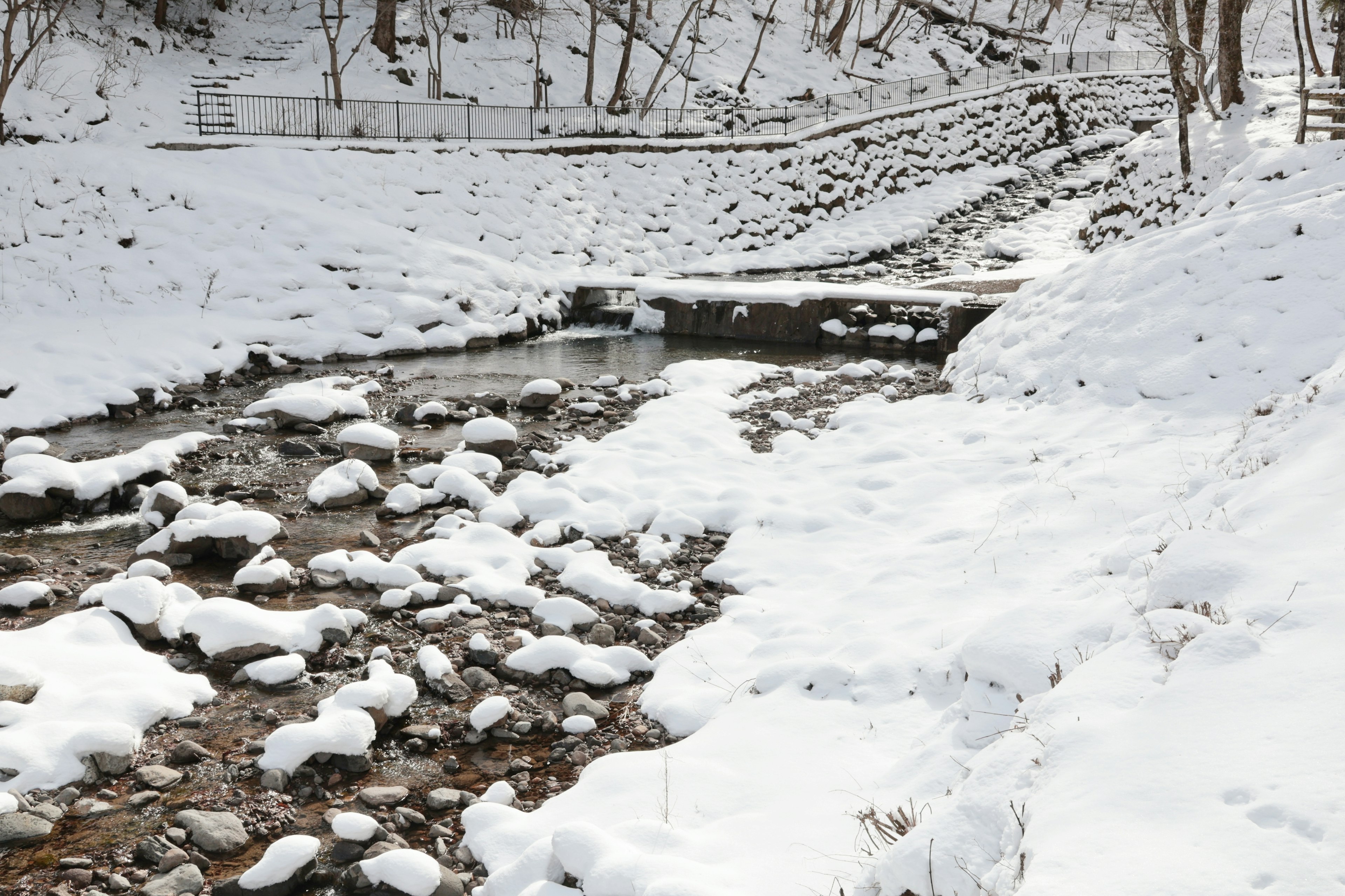 Arroyo cubierto de nieve con rocas y paisaje circundante