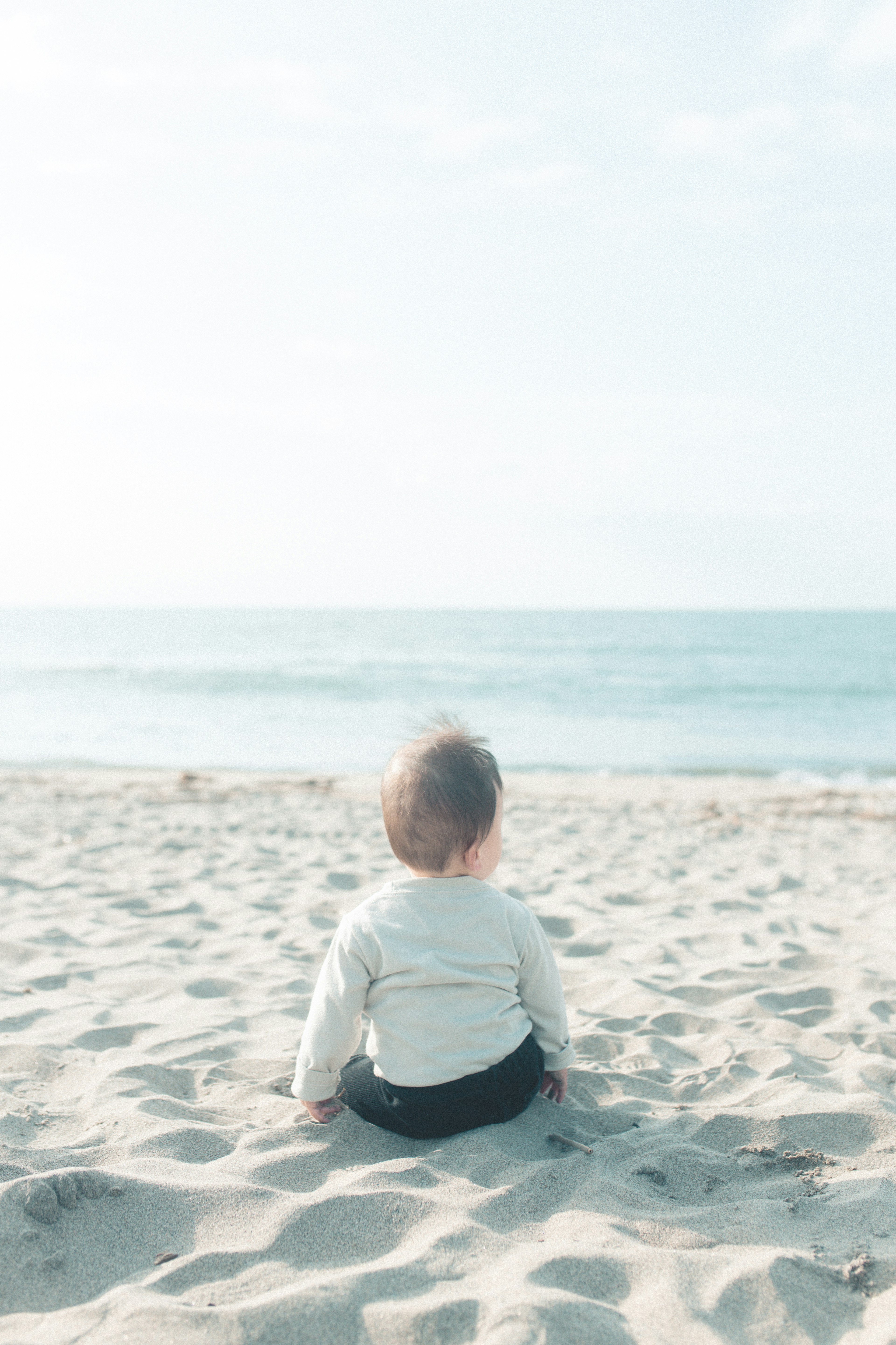 Baby sitzt am Strand und schaut auf den Ozean