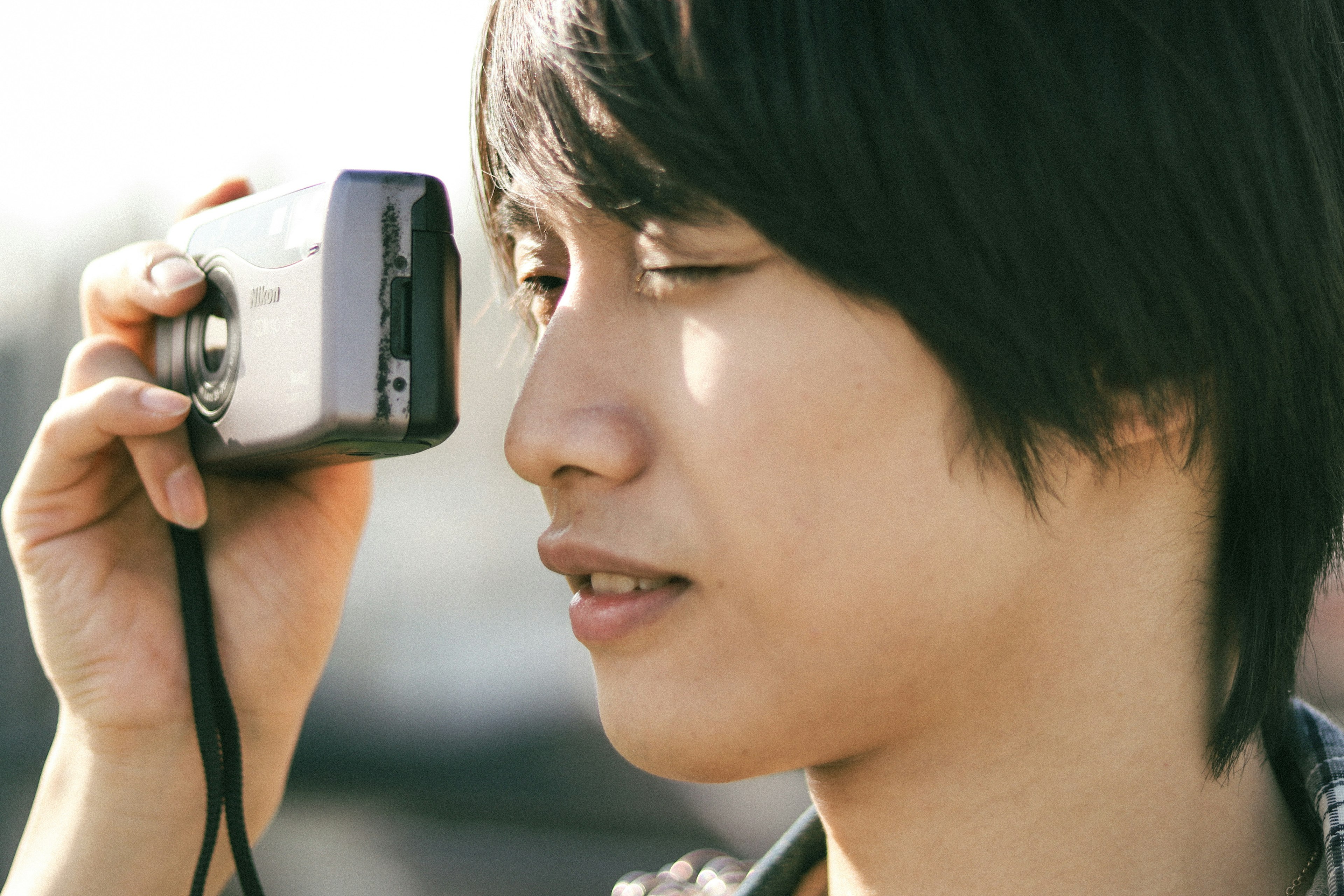 Giovane uomo che fa l'occhiolino mentre tiene una macchina fotografica