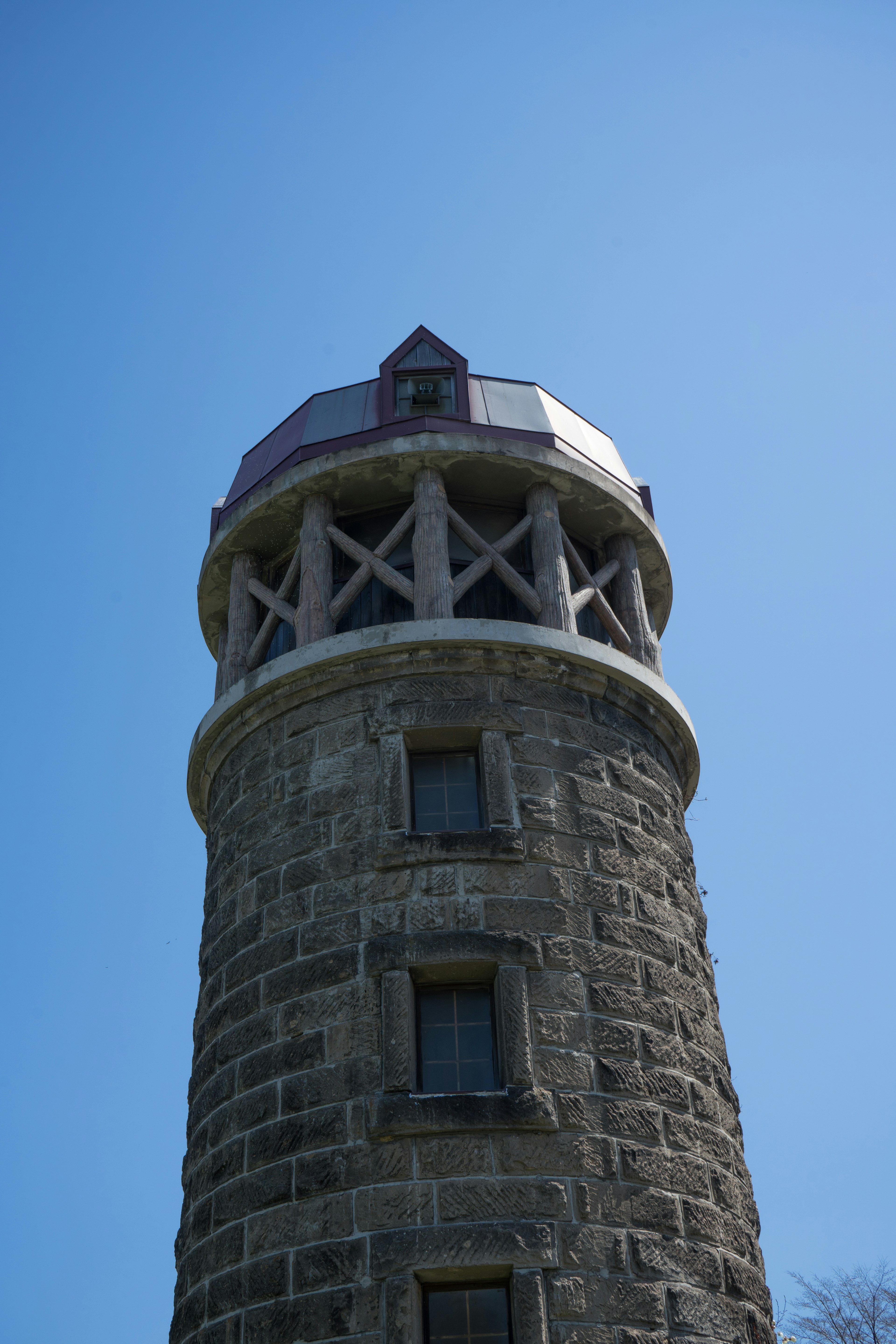 Photo of a stone tower featuring a unique roof and windows at the top