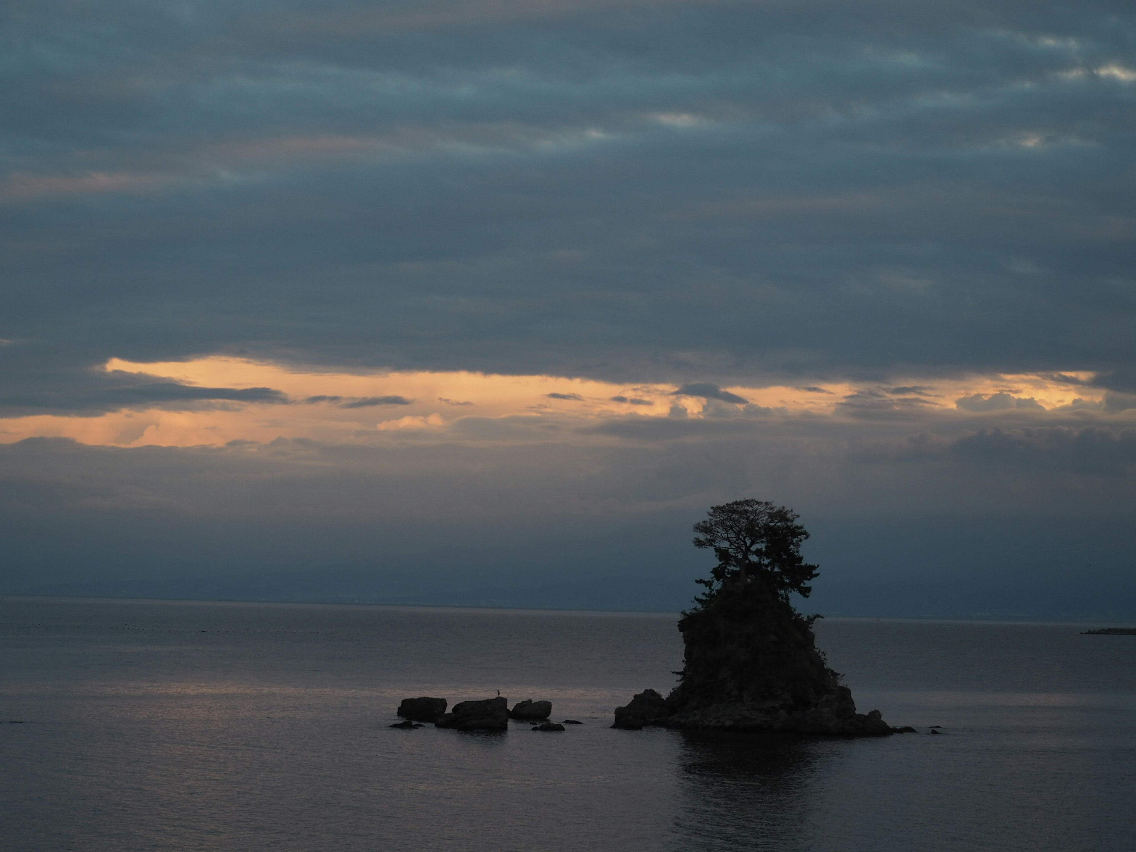 Eine kleine Insel mit einem Baum, die auf einem ruhigen Meer unter einem Dämmerungshimmel schwebt