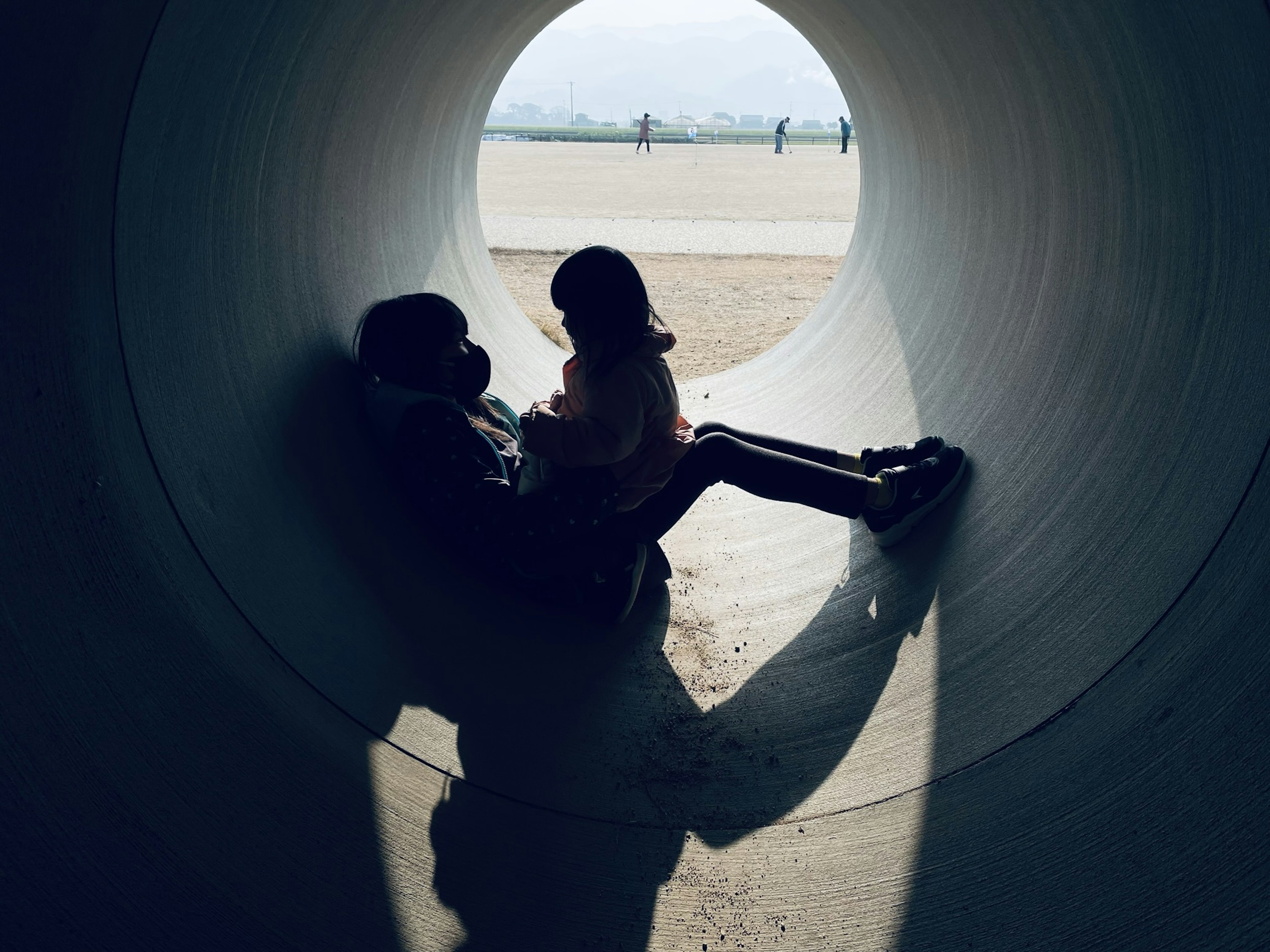 Silhouette of a child and adult playing inside a tunnel