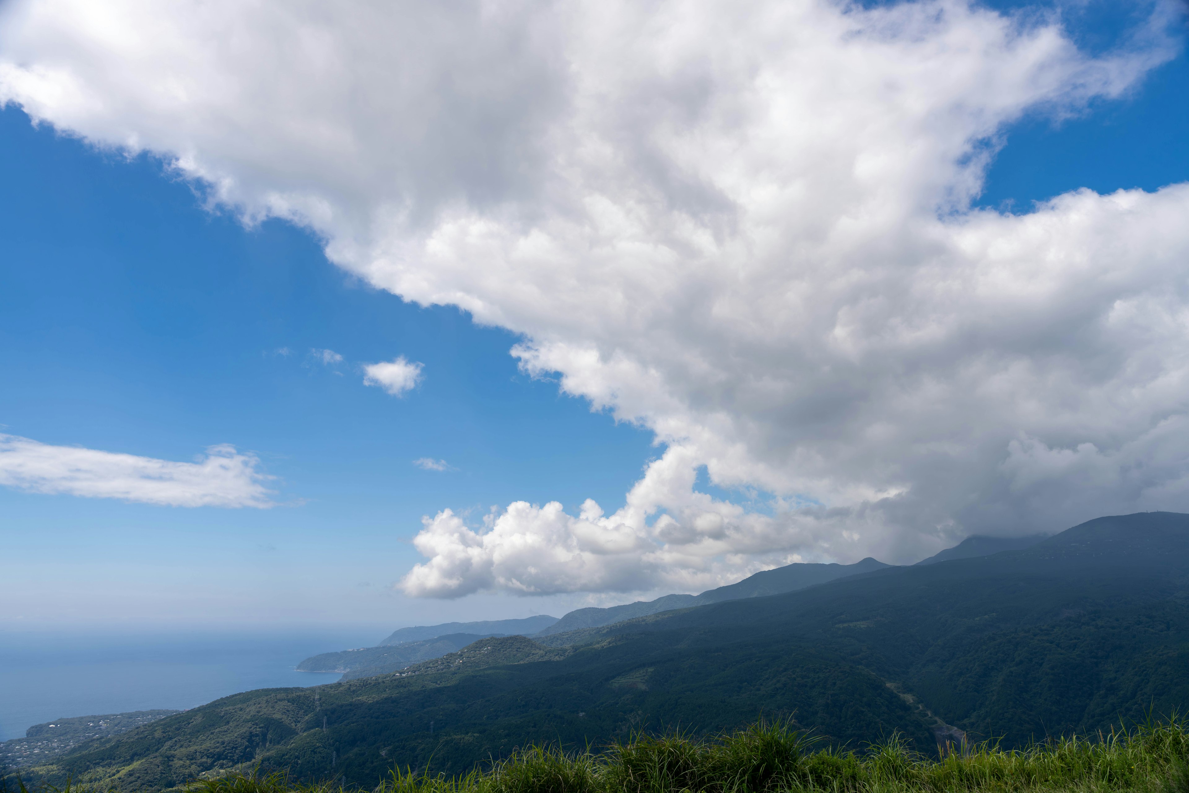 青い空と白い雲の広がる風景、山と海の美しい景色