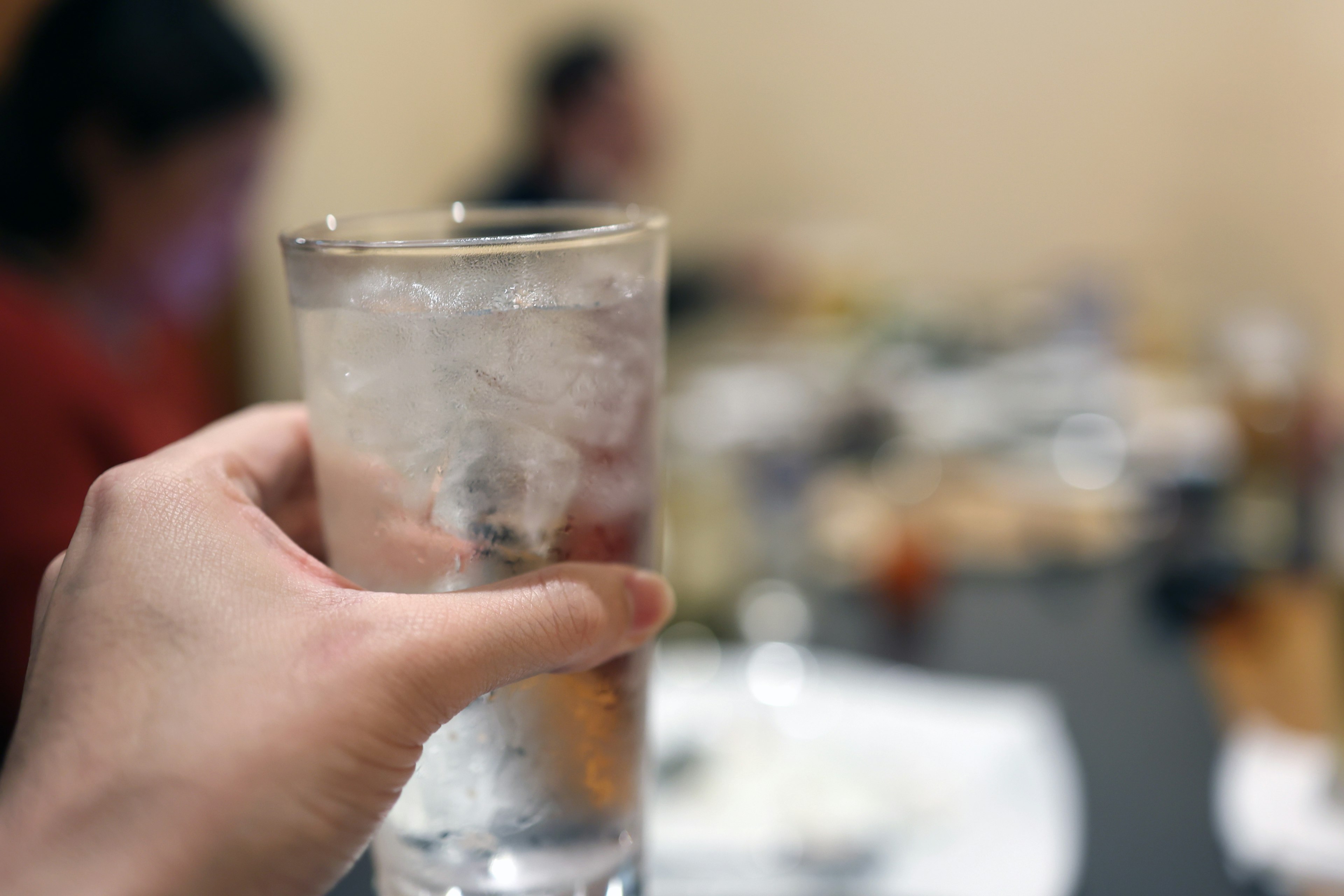 A hand holding a glass of ice water