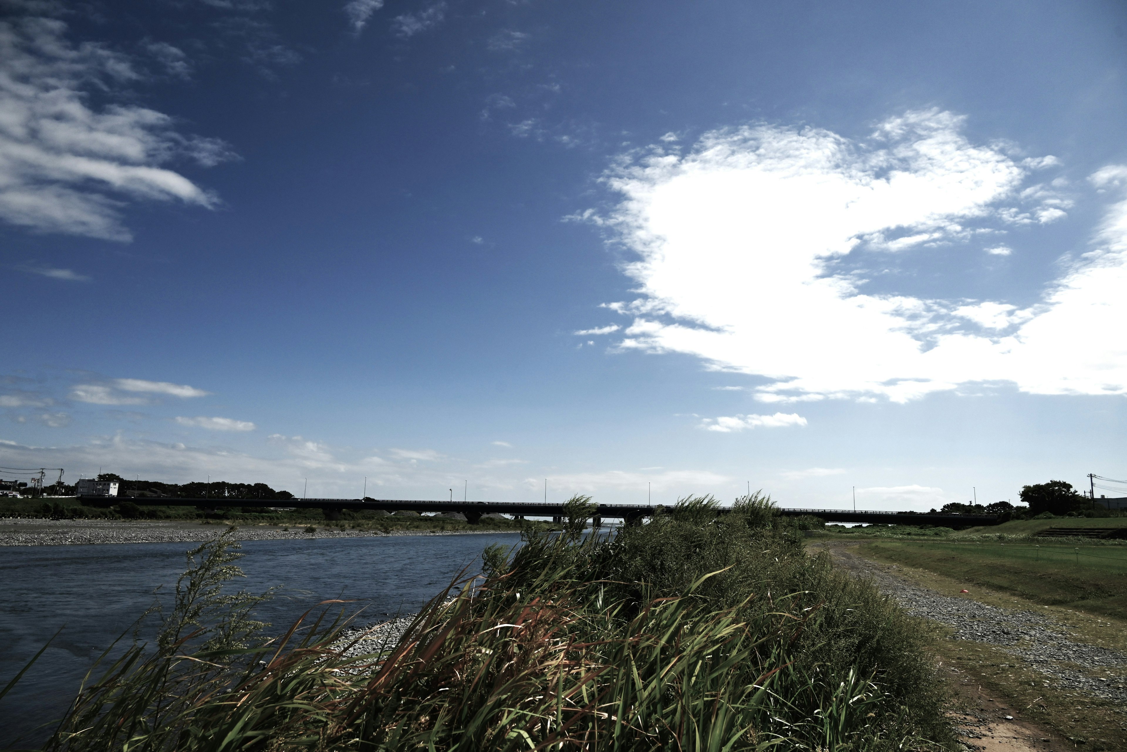 Scenic riverside view with blue sky and white clouds