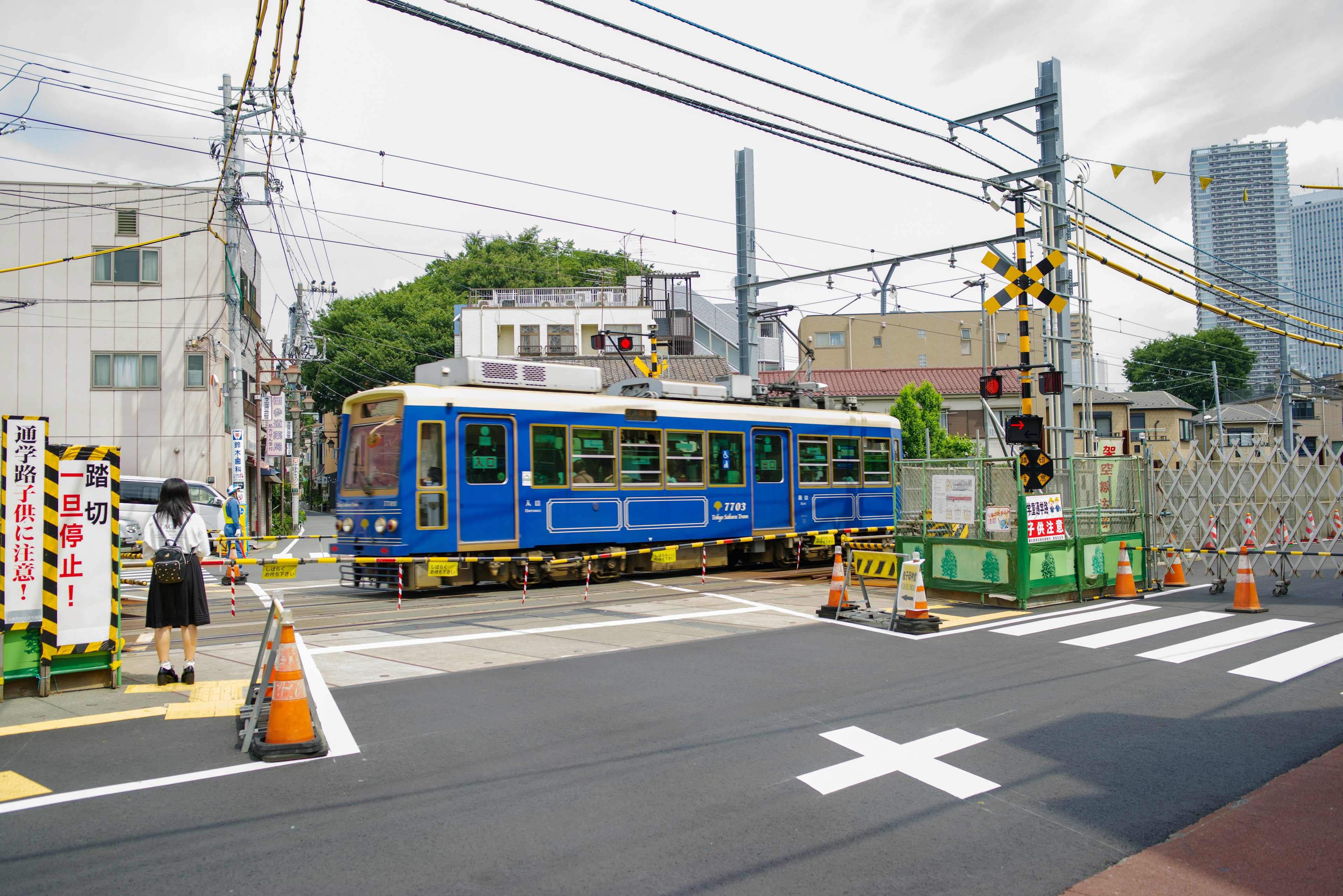 Un tram blu che passa attraverso un incrocio con lavori in corso e segnali stradali nelle vicinanze