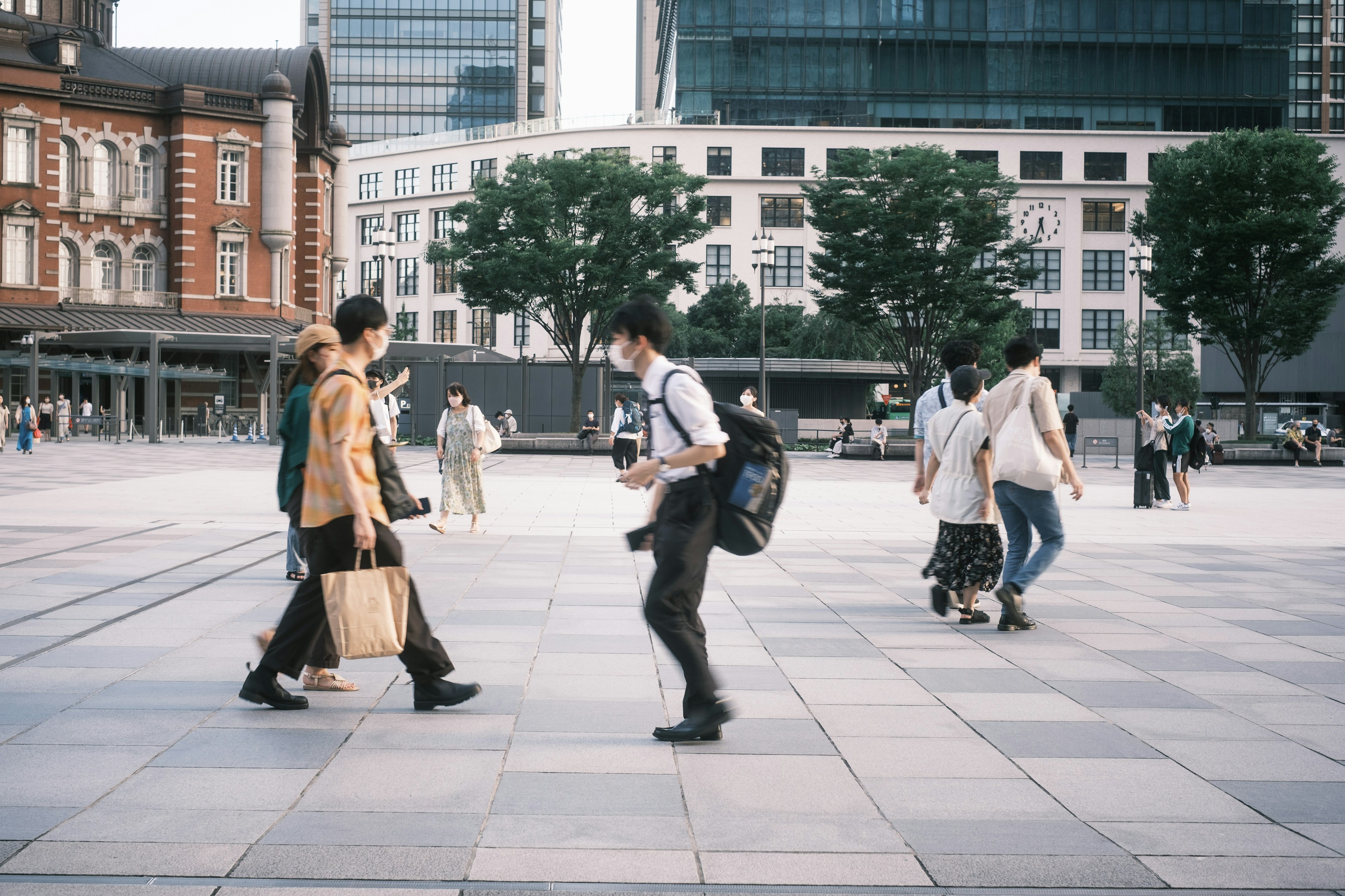 Personas caminando en una plaza urbana con edificios modernos al fondo