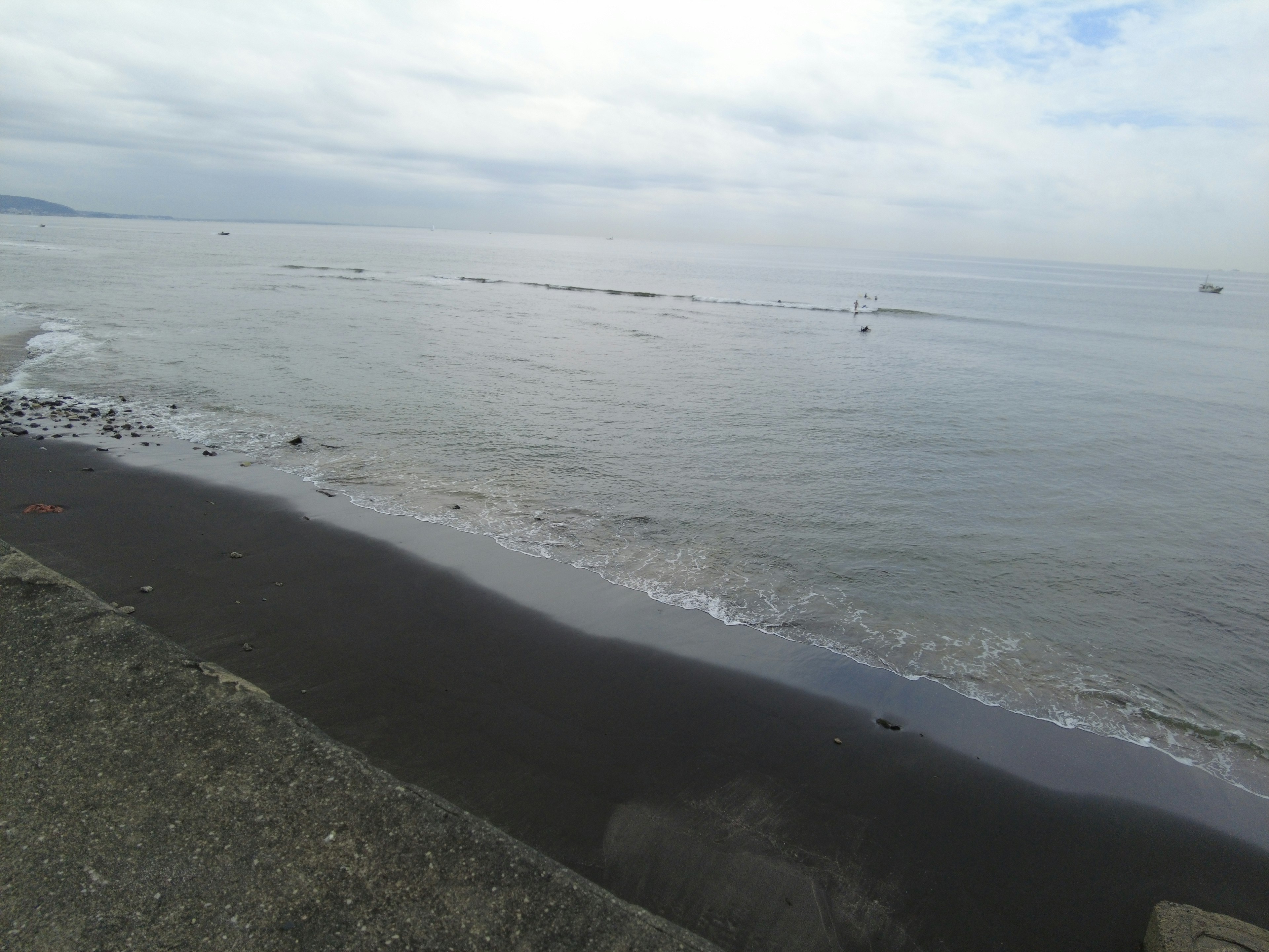 Schwarzer Sandstrand mit ruhigen Wellen