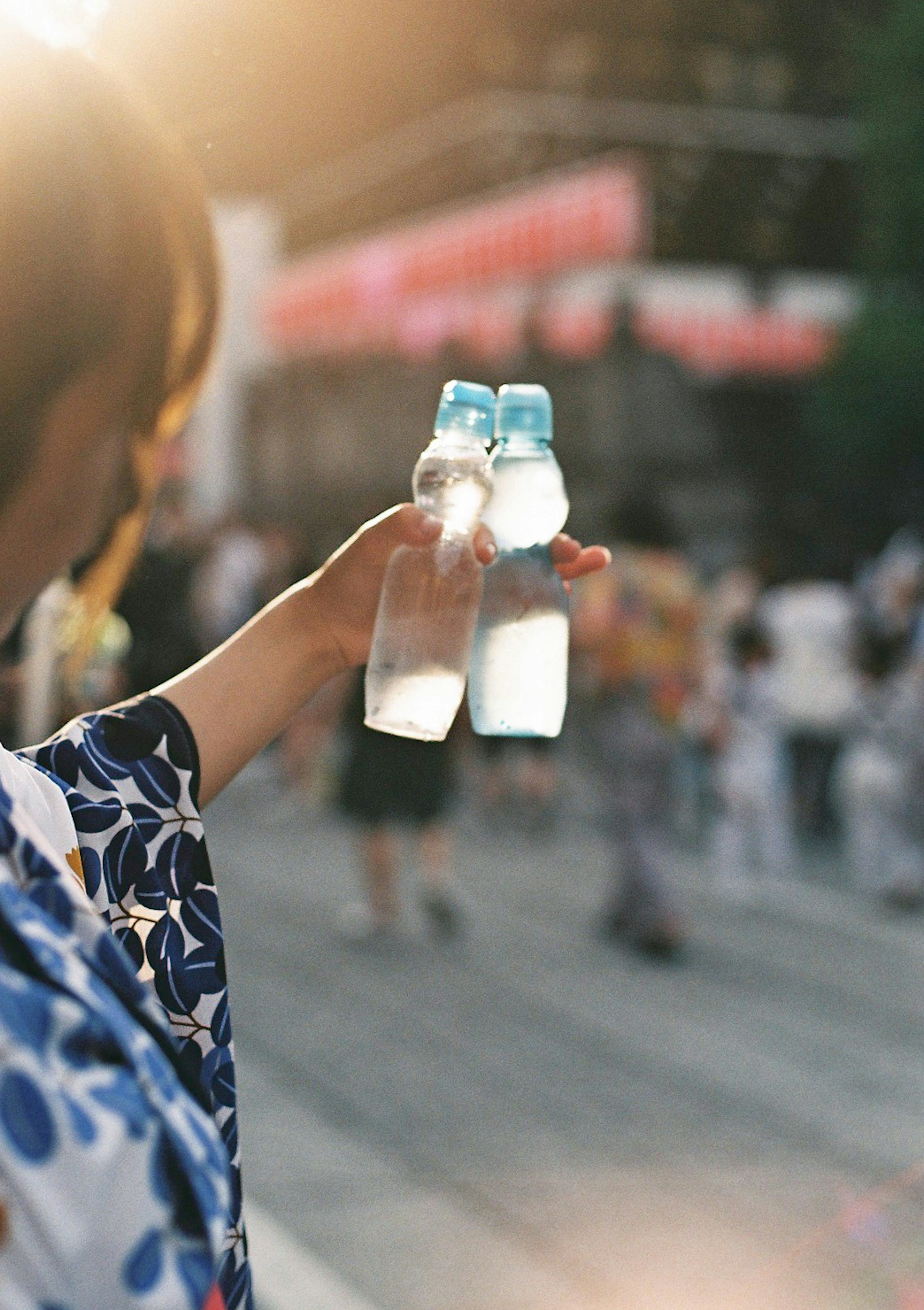 Une femme tenant deux bouteilles d'eau avec des gens en arrière-plan