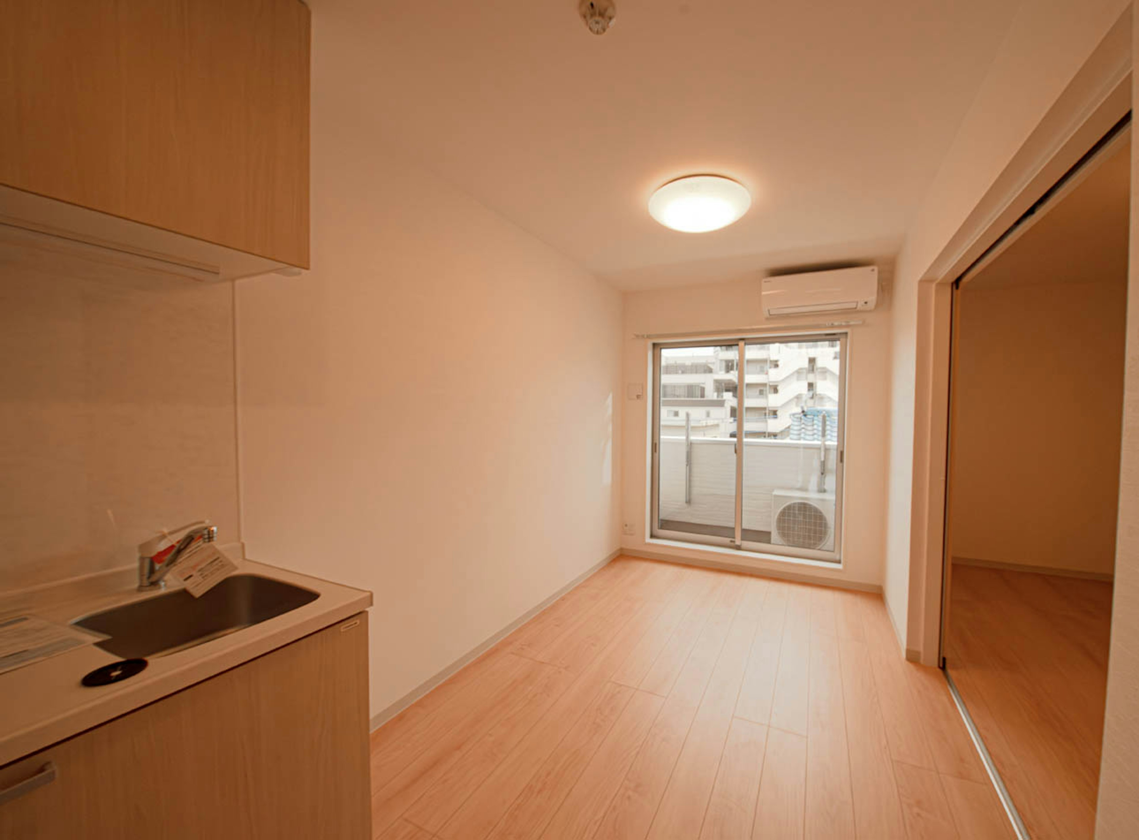 Simple modern studio apartment interior featuring kitchen area and large window