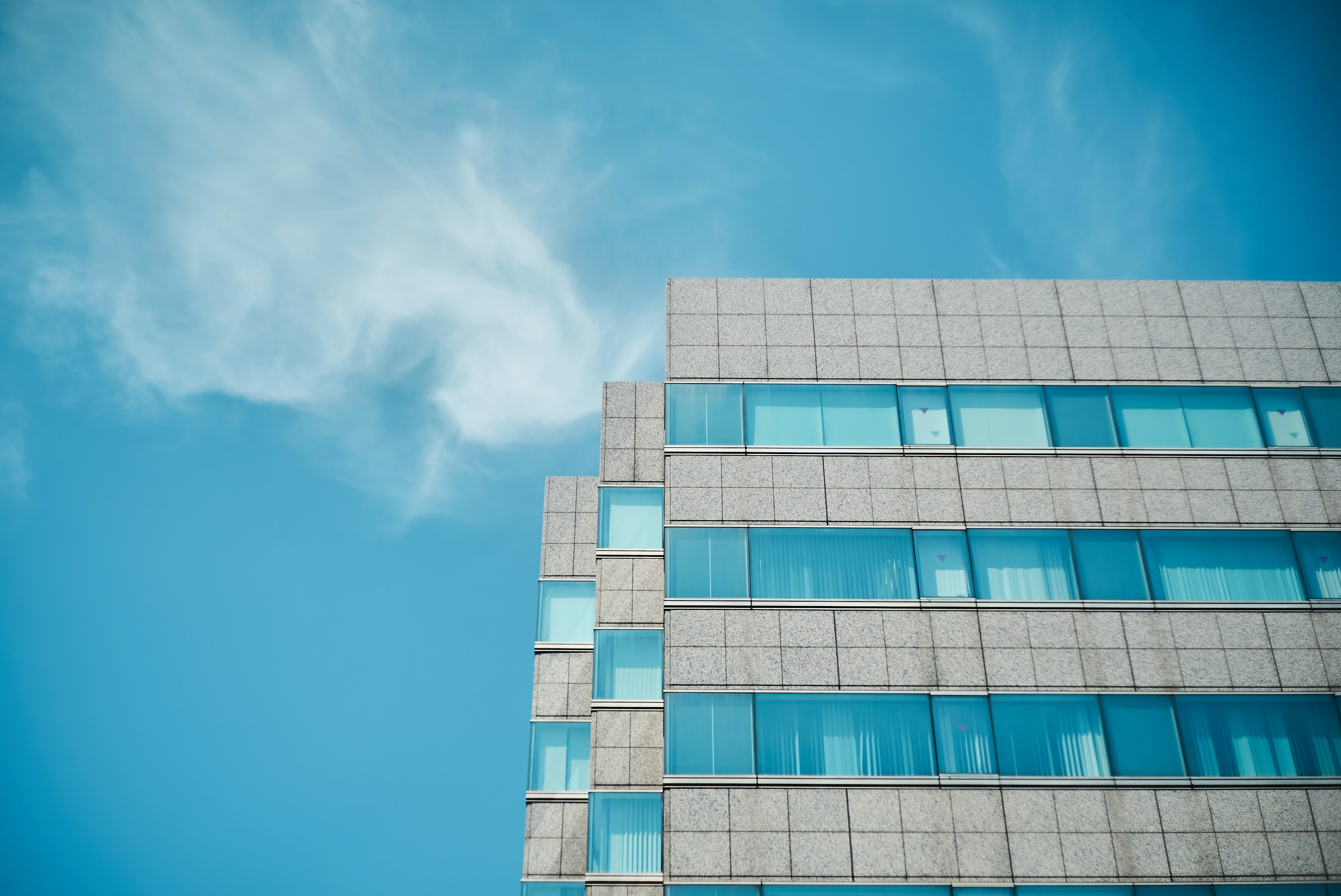 Bagian atas gedung modern di bawah langit biru