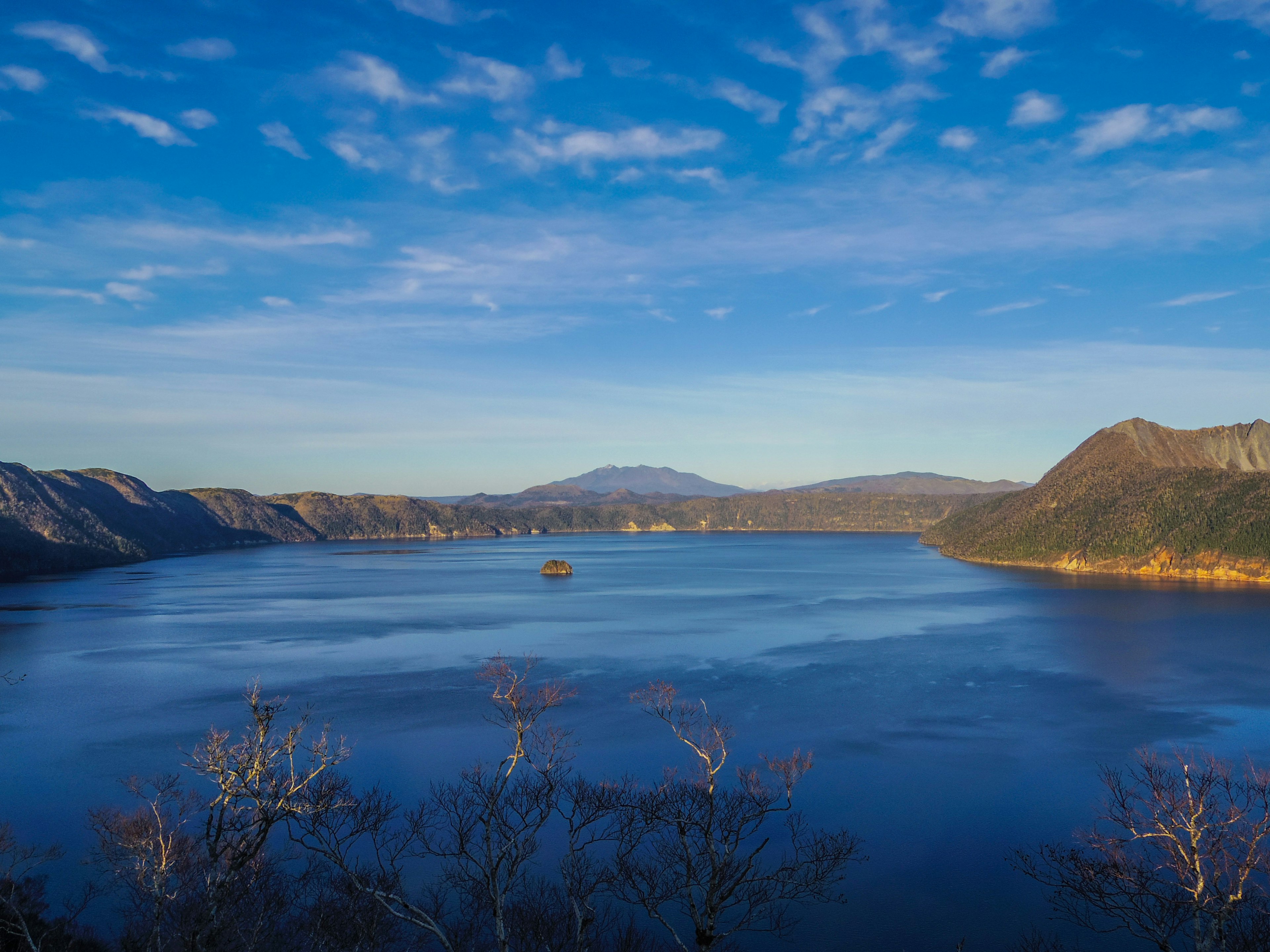 Panoramablick auf einen blauen See umgeben von Bergen unter einem klaren Himmel