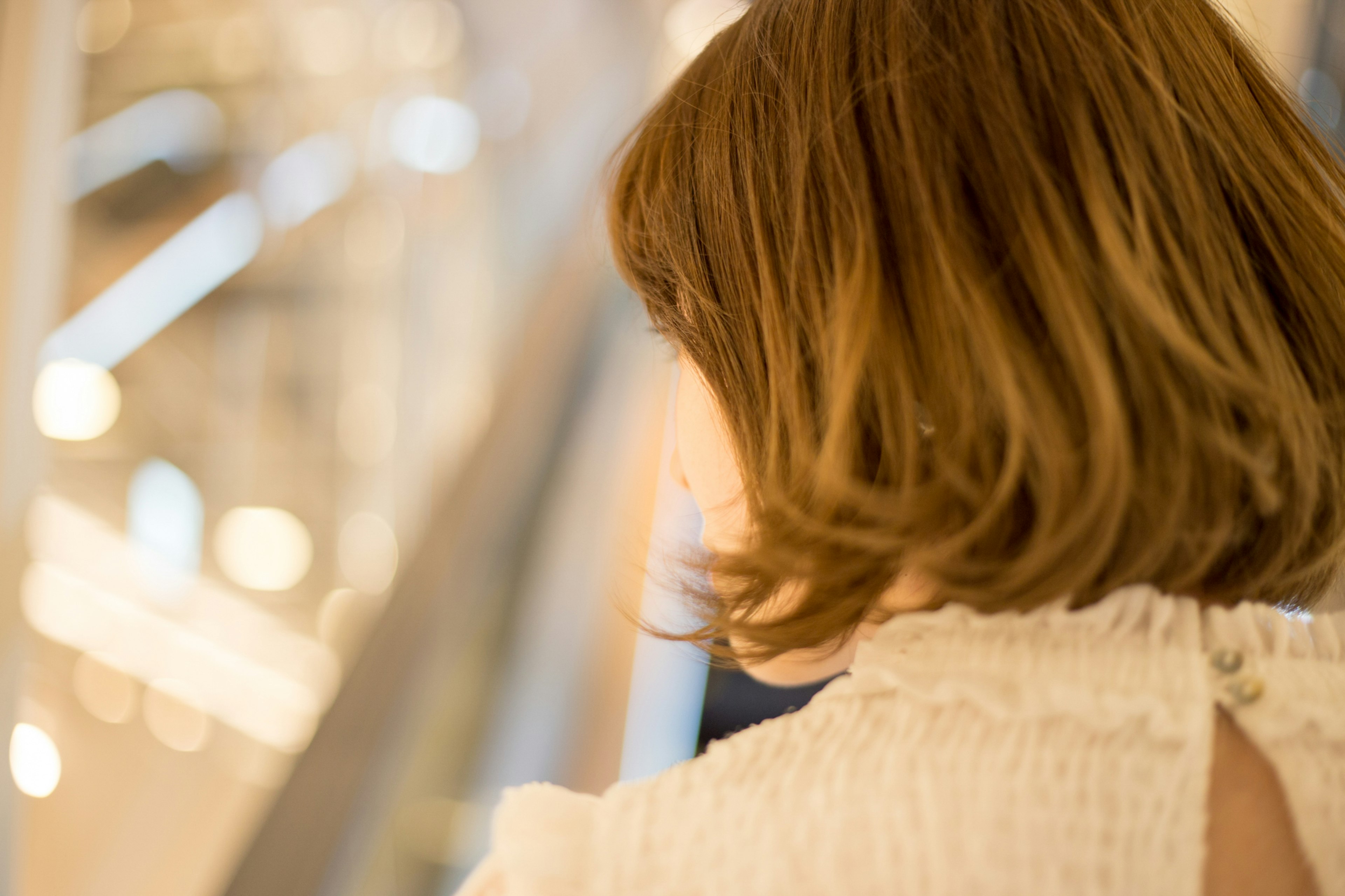 A woman with a bob hairstyle seen from behind in a bright background