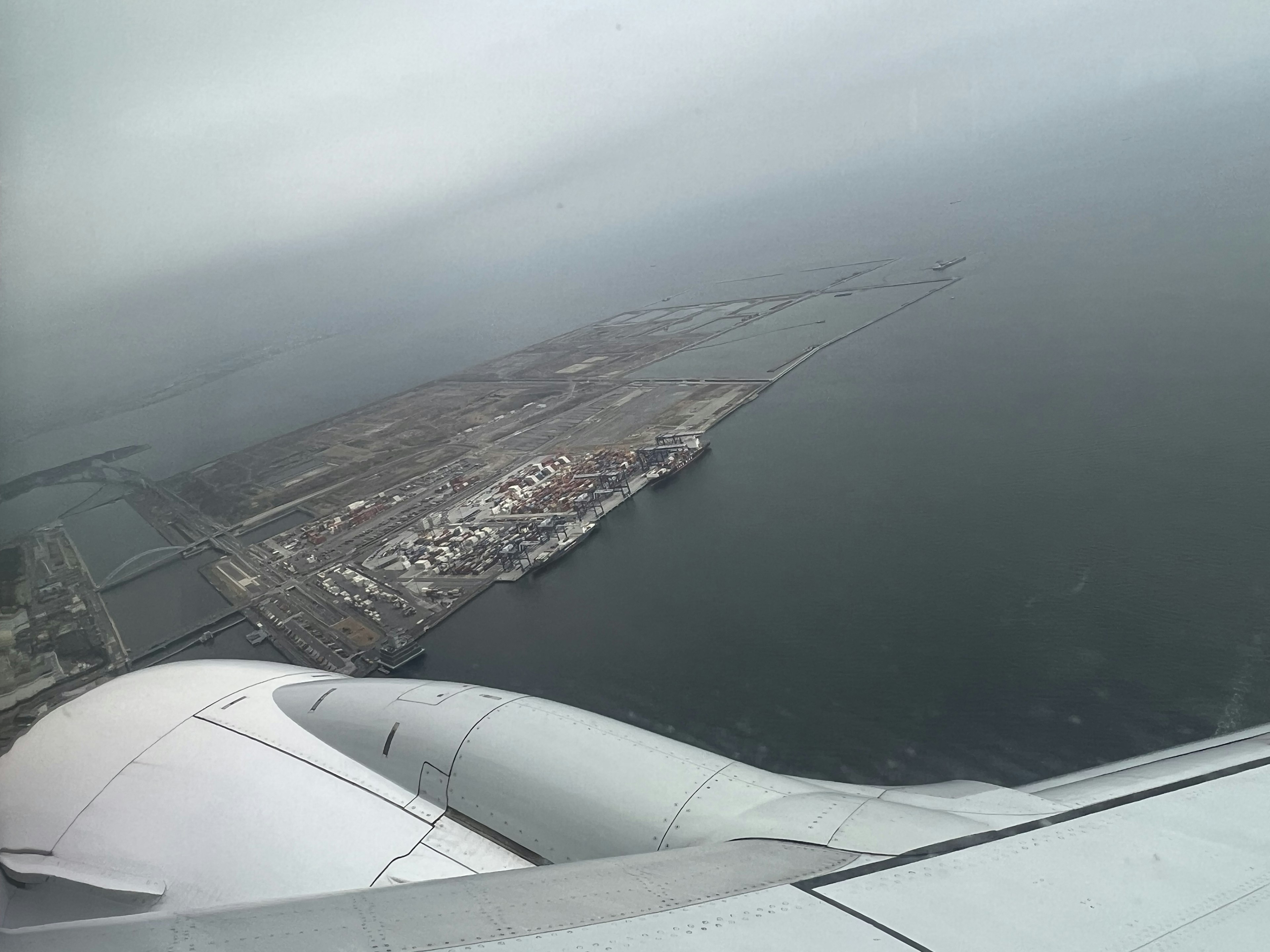 Aerial view of a coastal city with a visible shoreline from an airplane window