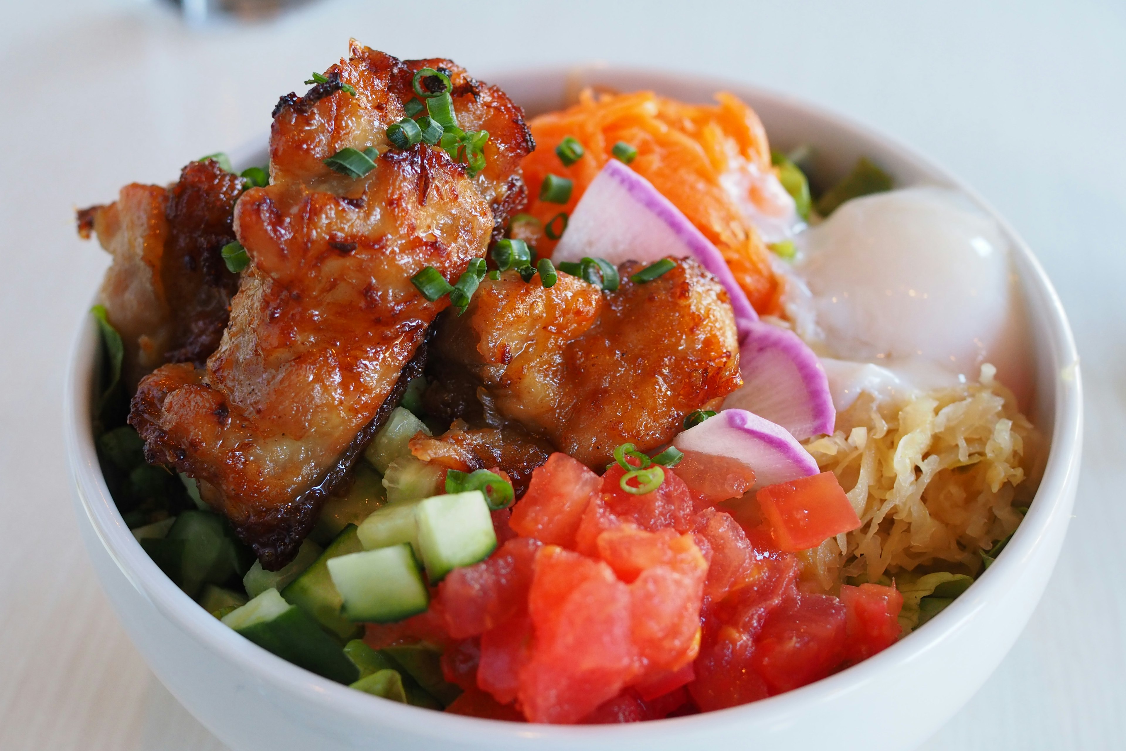 A delicious bowl dish with colorful toppings including chicken, vegetables, and eggs