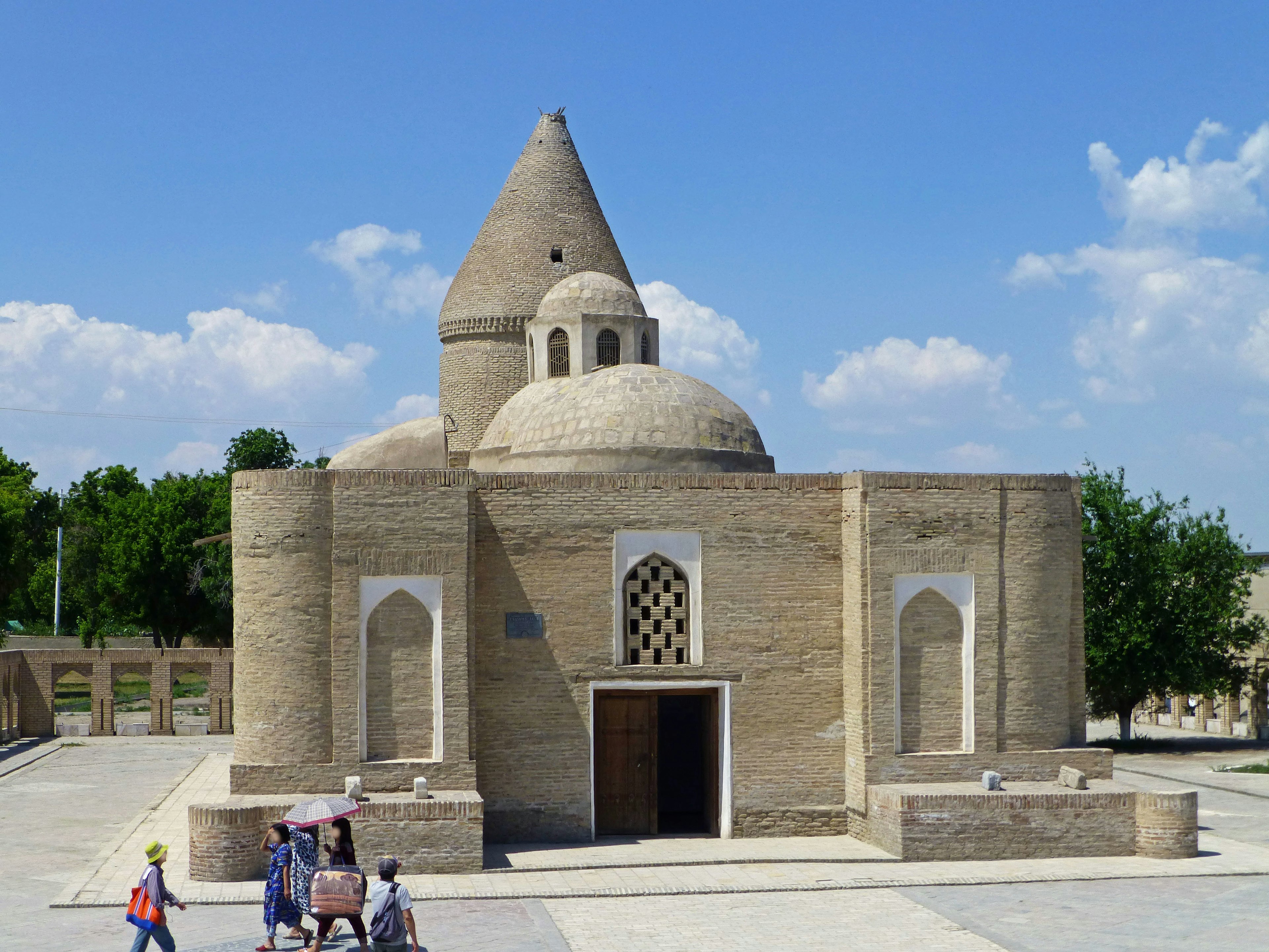 Ancient building under blue sky with people walking nearby