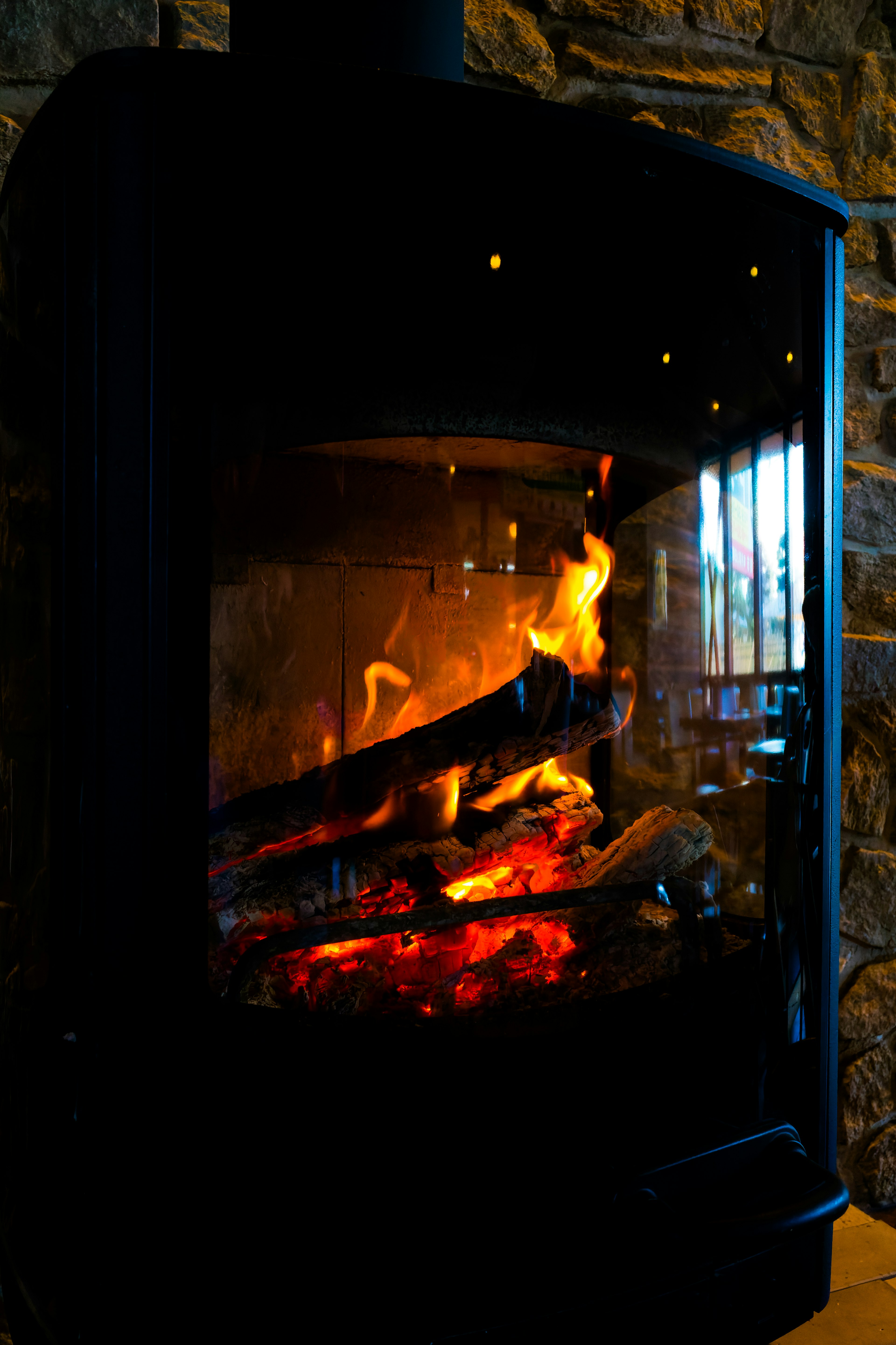 Black fireplace with burning logs and stone wall