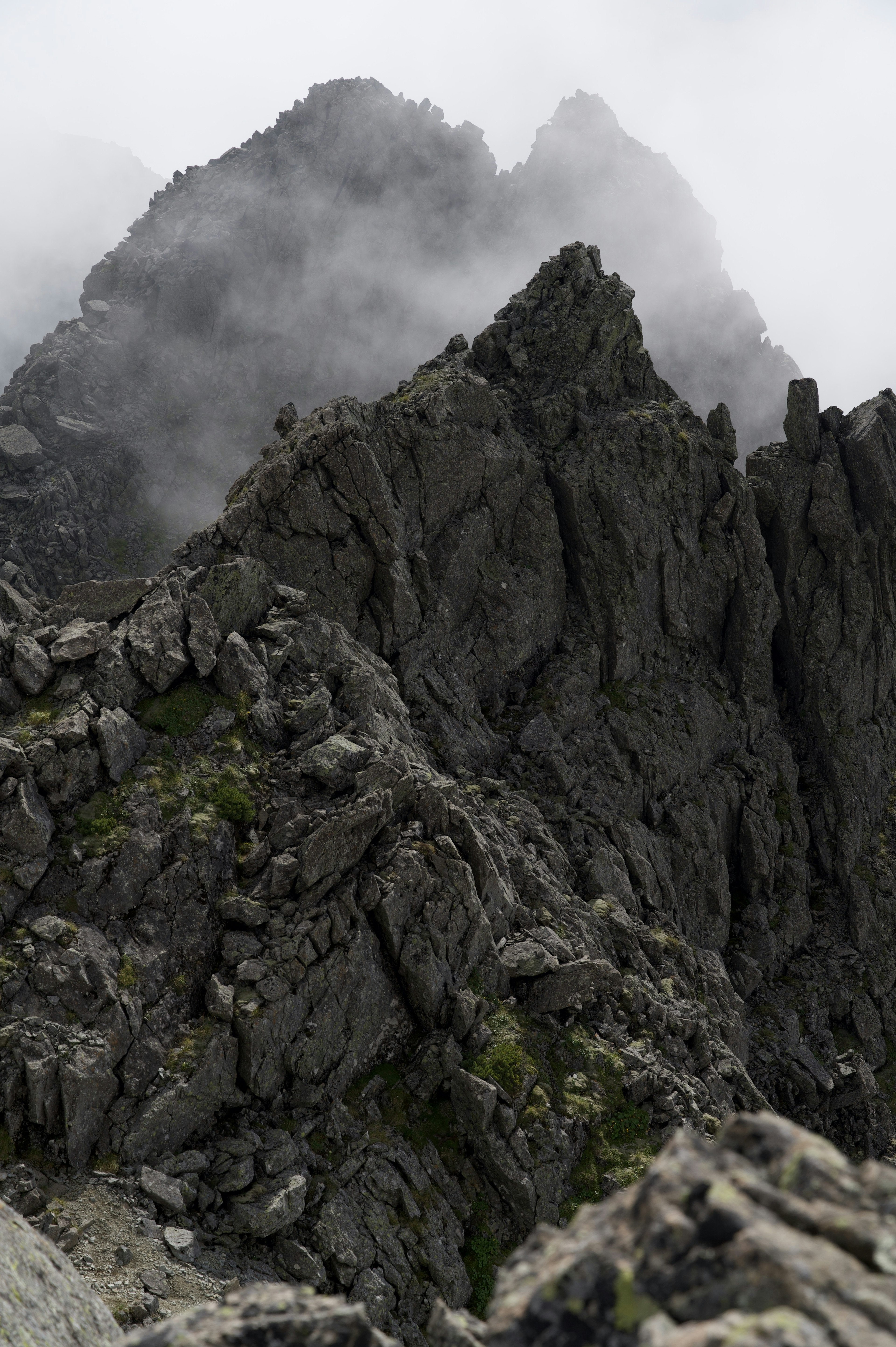 Ein zerklüfteter Berggipfel, umhüllt von Nebel und Wolken