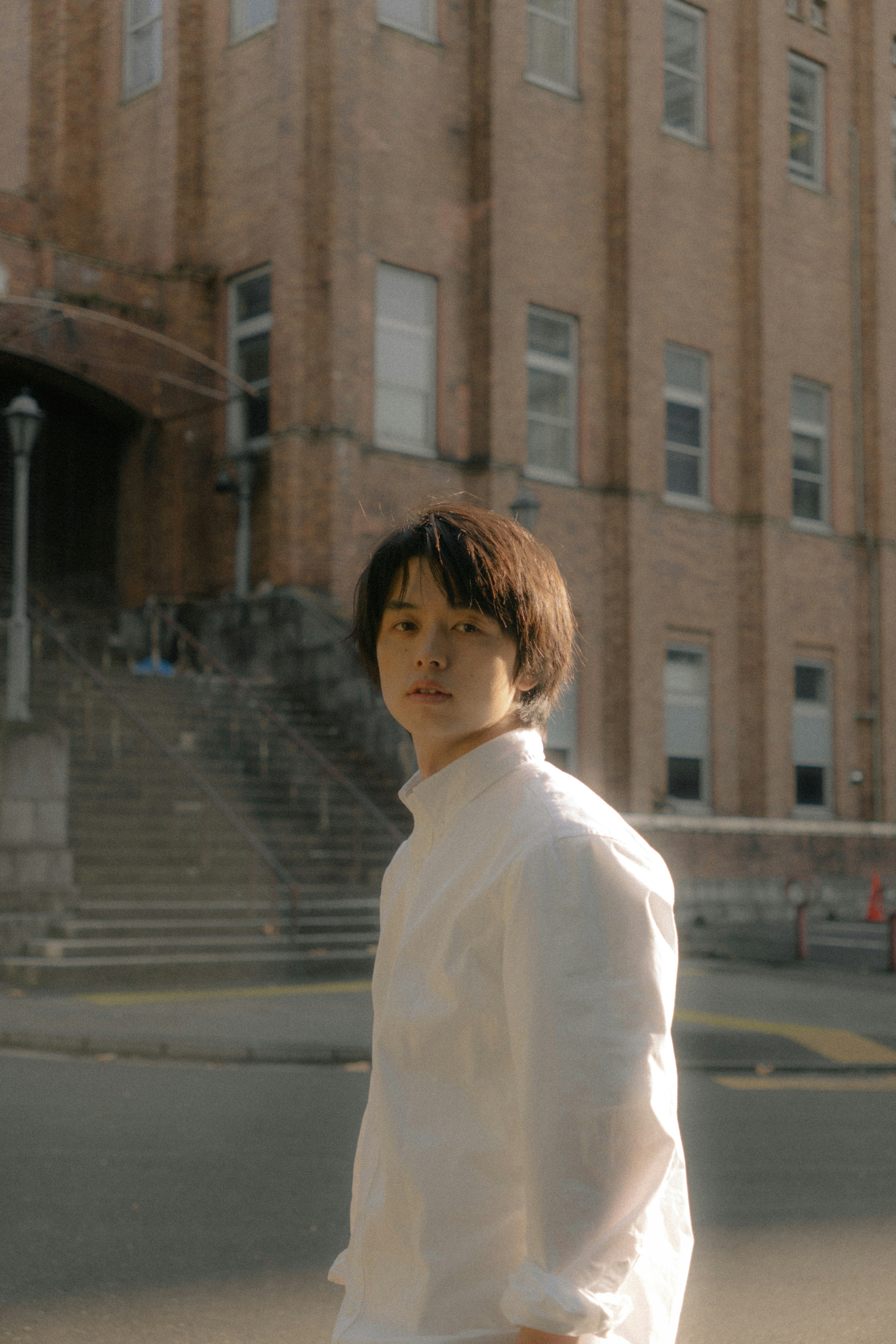 Young man in white shirt standing in front of an old building