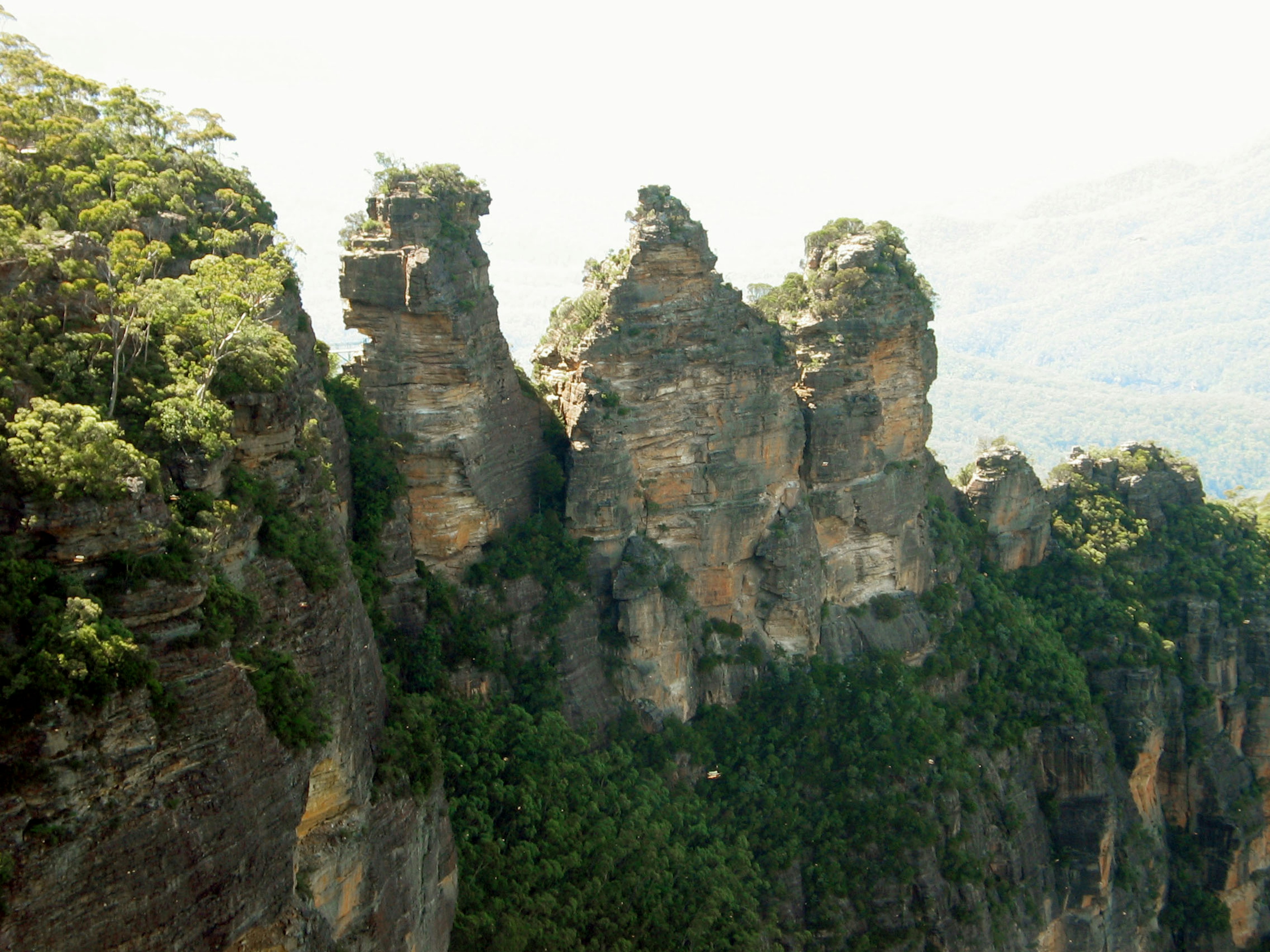 Un trio de formations rocheuses sous un ciel bleu entouré d'une végétation luxuriante