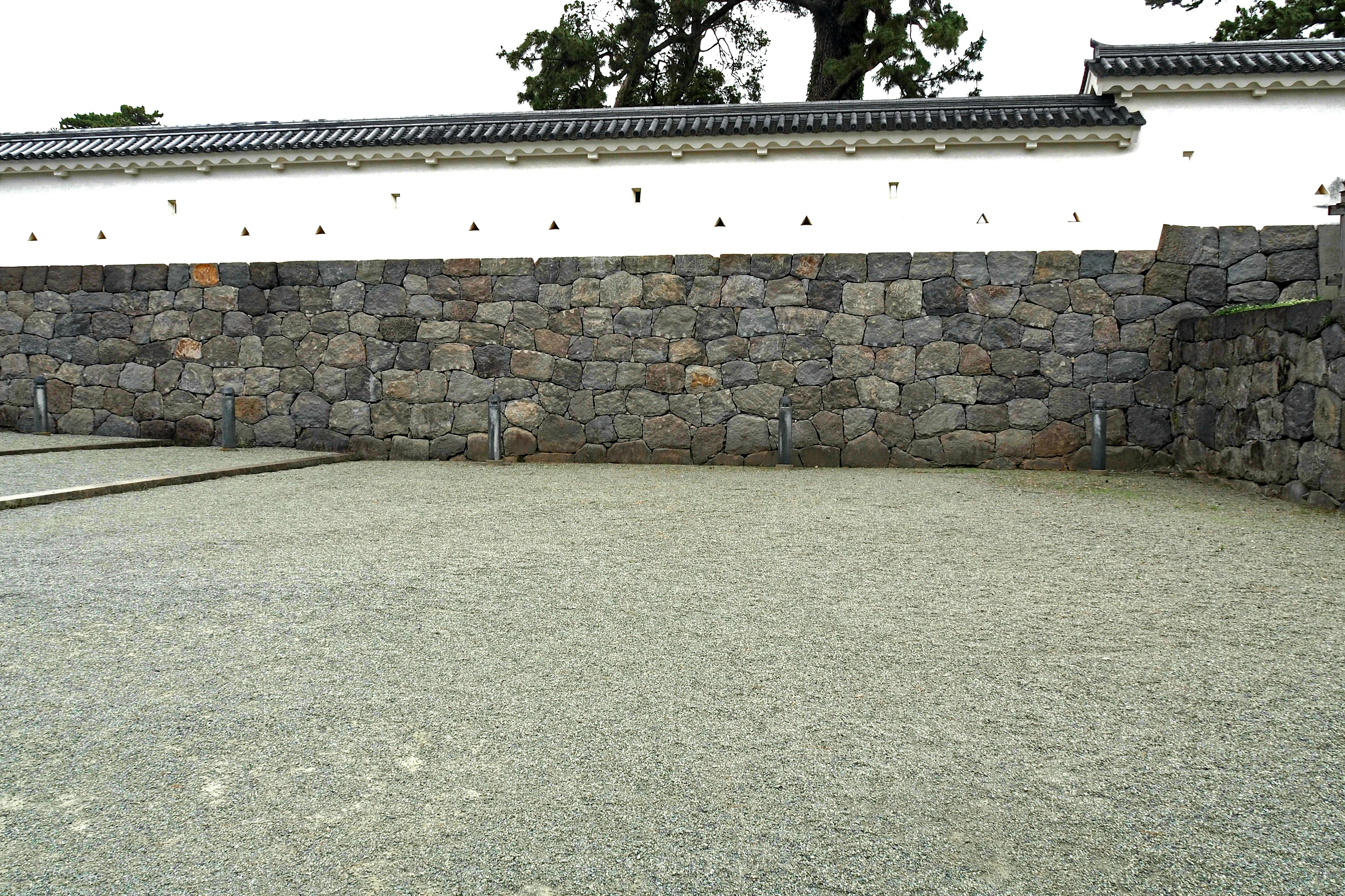 Un jardín tranquilo con una pared de piedra y una cerca blanca