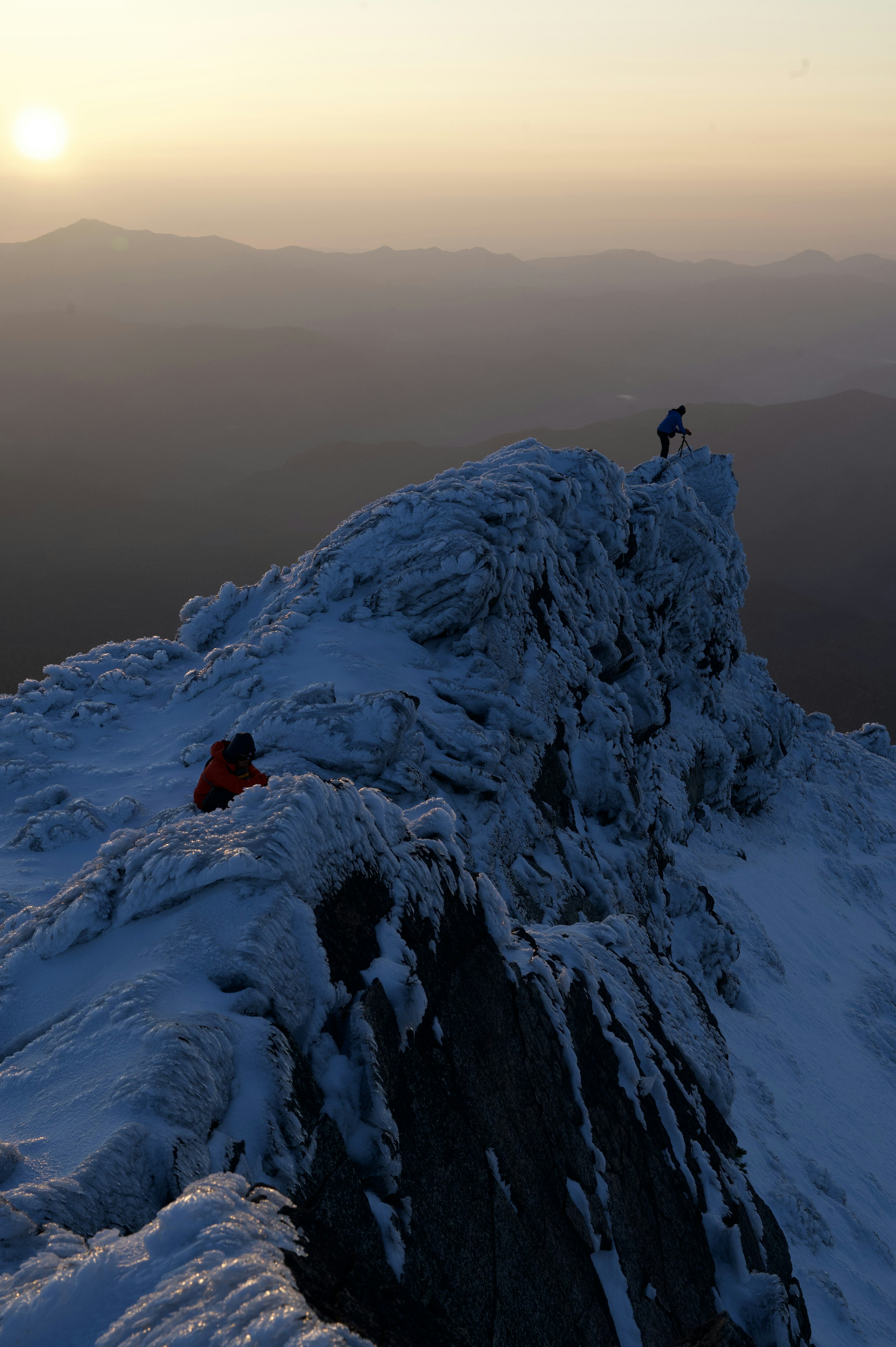 Escaladores en una cima nevada al atardecer