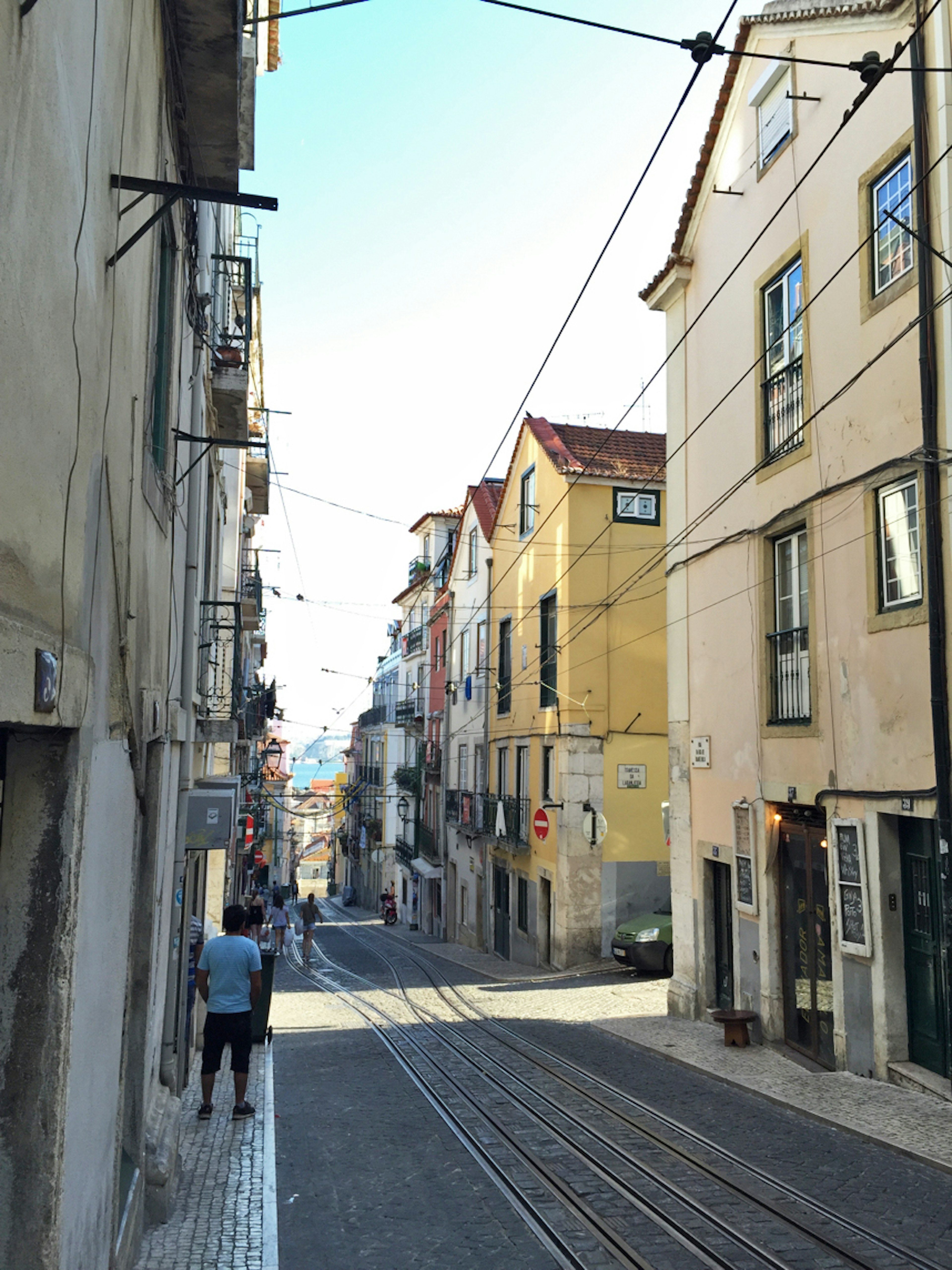 Rue étroite à Lisbonne avec des bâtiments colorés et des rails de tram