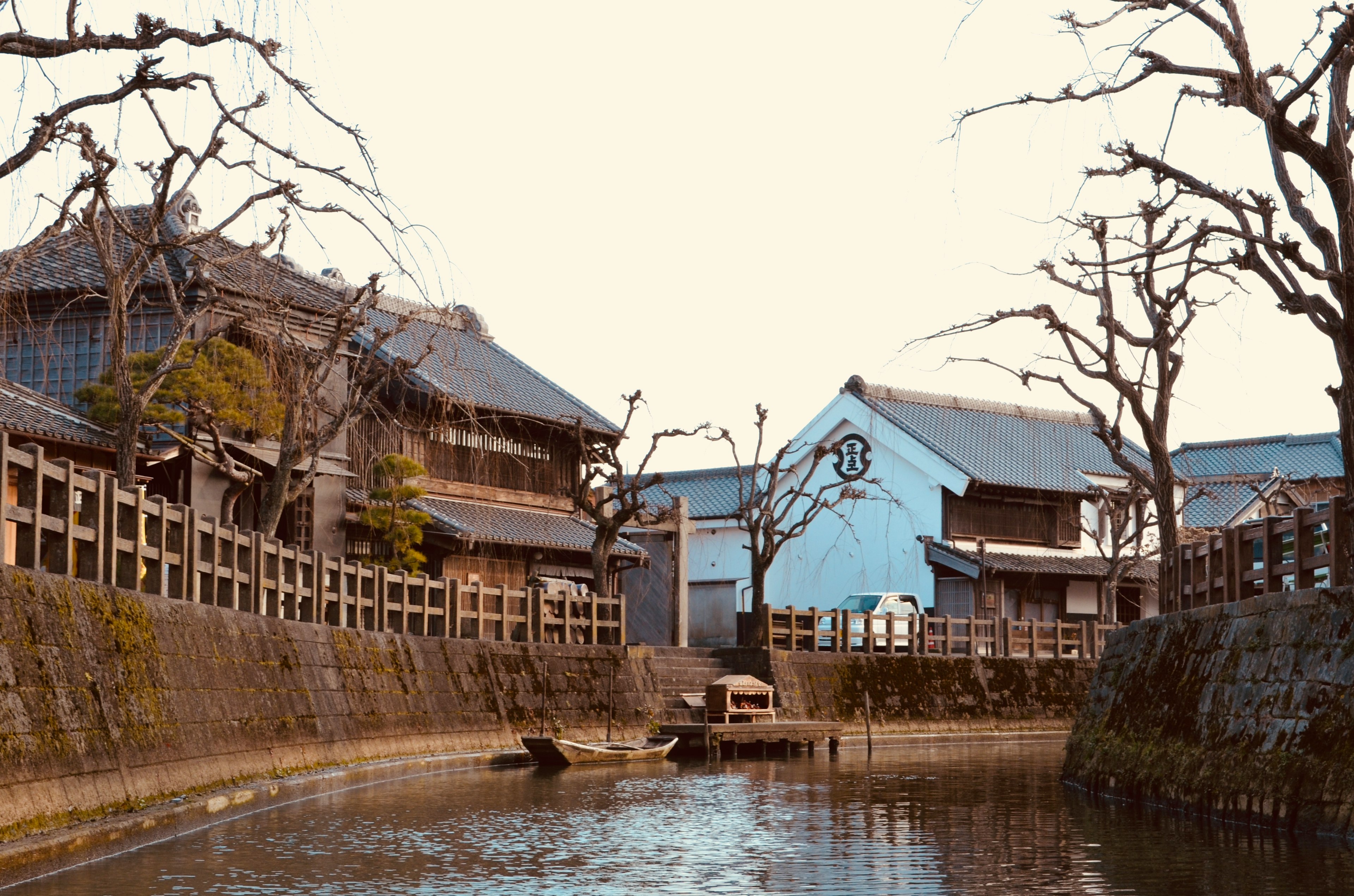 Quiet riverside view featuring old wooden houses and bare trees