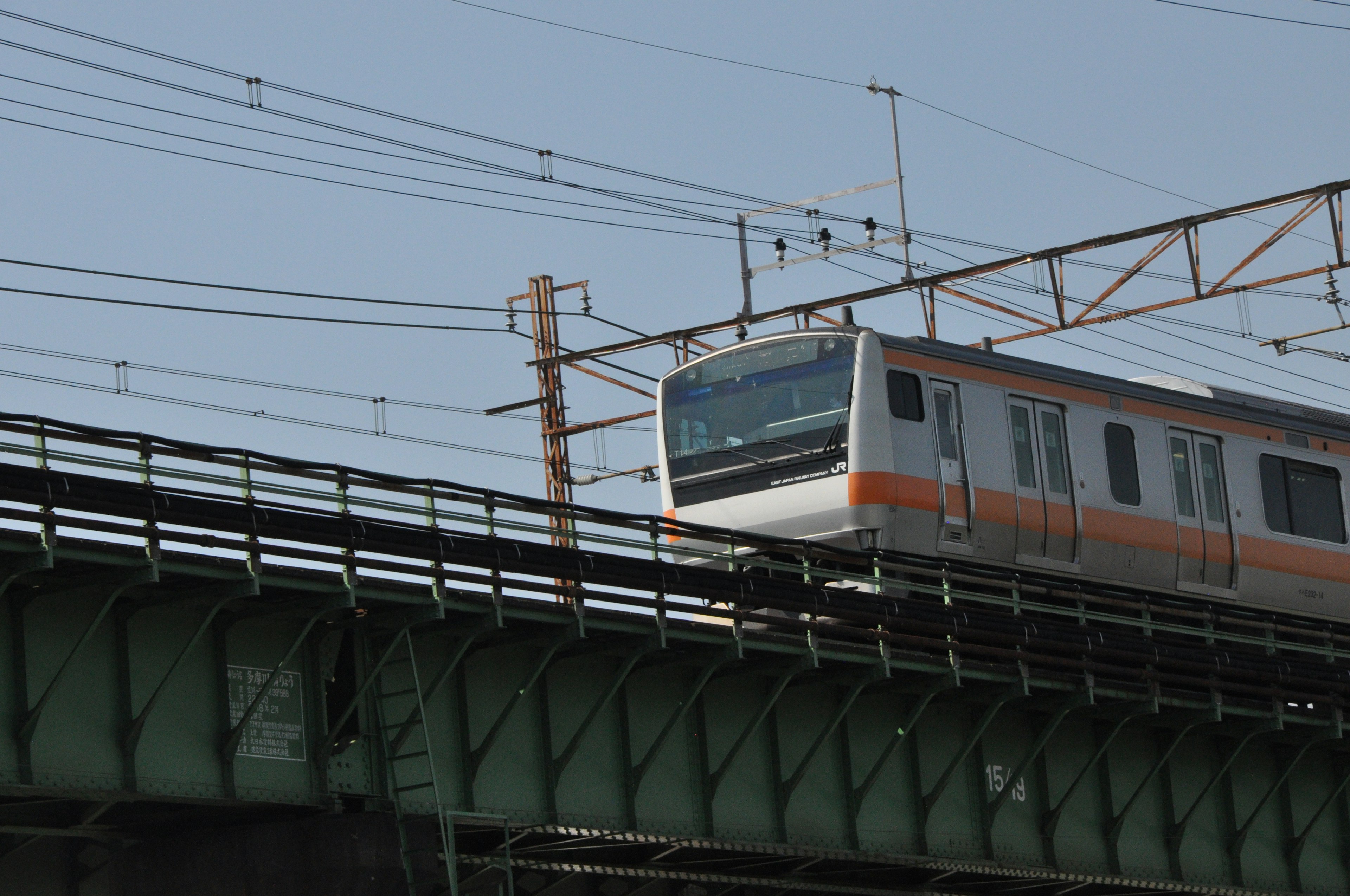 Tren naranja y blanco circulando por una vía elevada