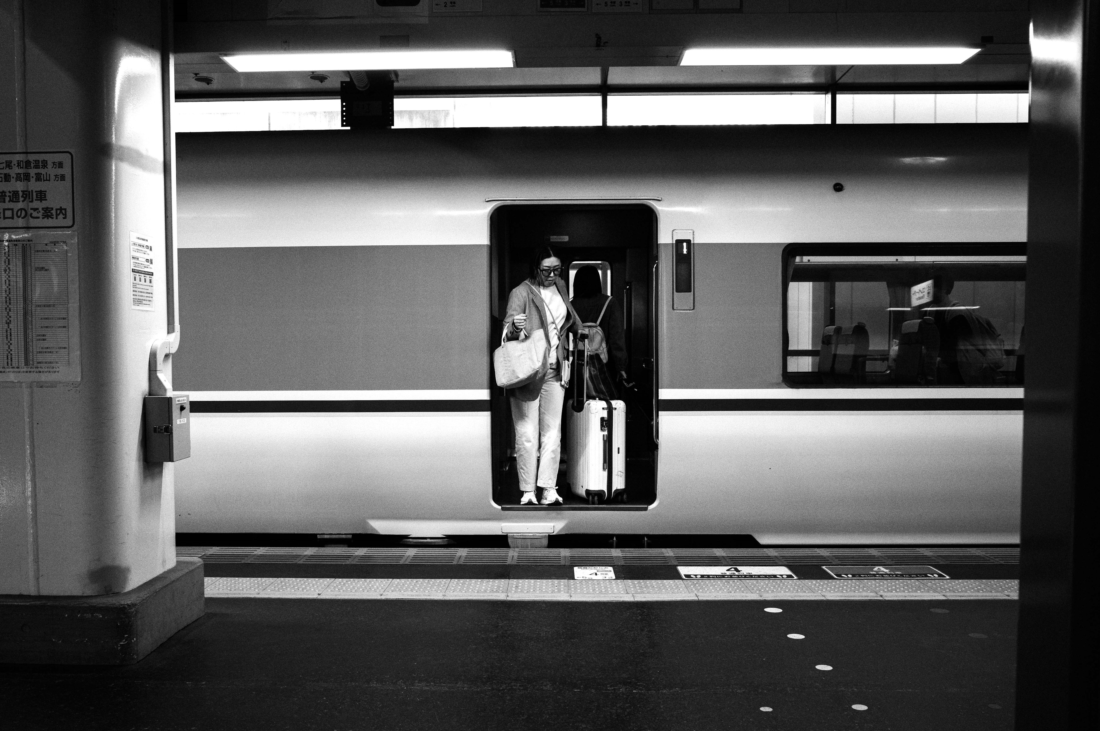 Persona de pie en la puerta de un tren en blanco y negro con equipaje