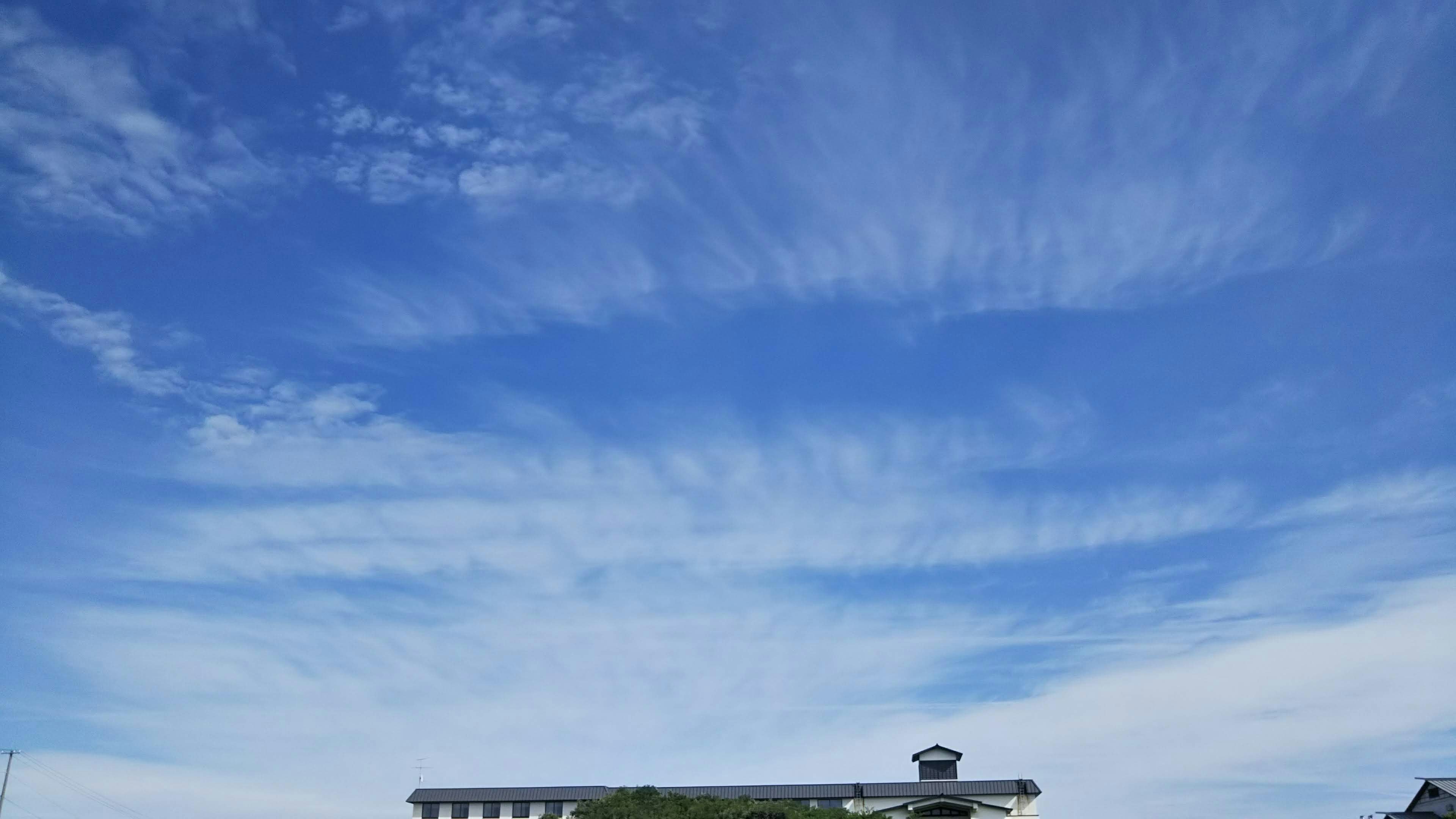 Un edificio contrasta con un cielo azul y nubes blancas