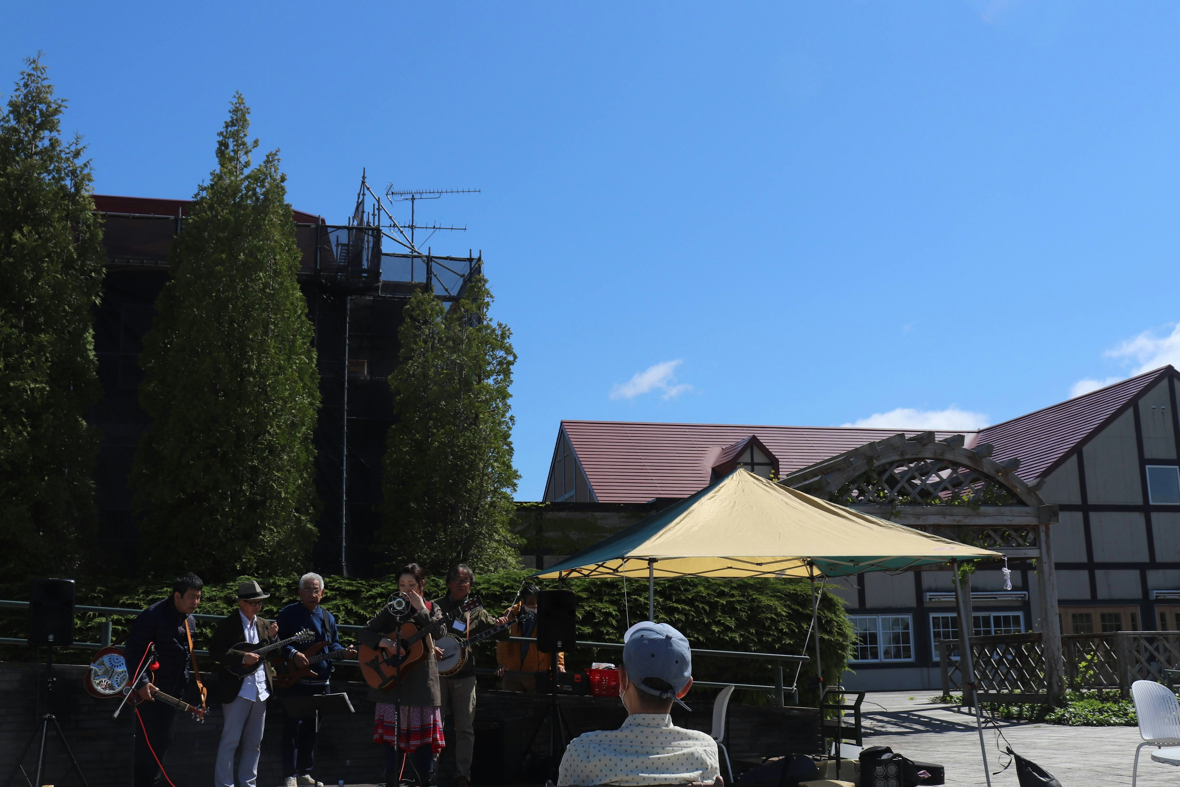 Band performing under a clear blue sky with audience