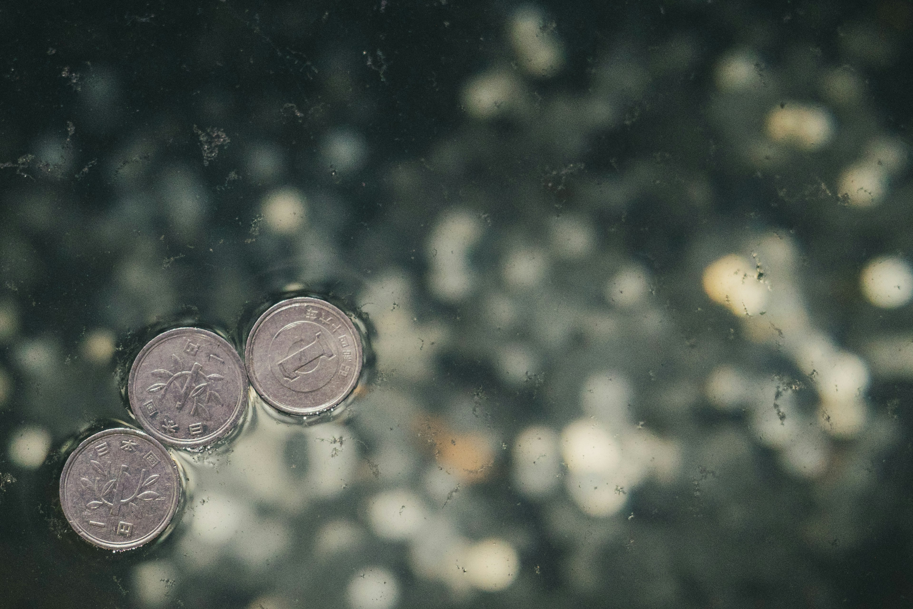 Tres monedas flotando en agua con un fondo borroso