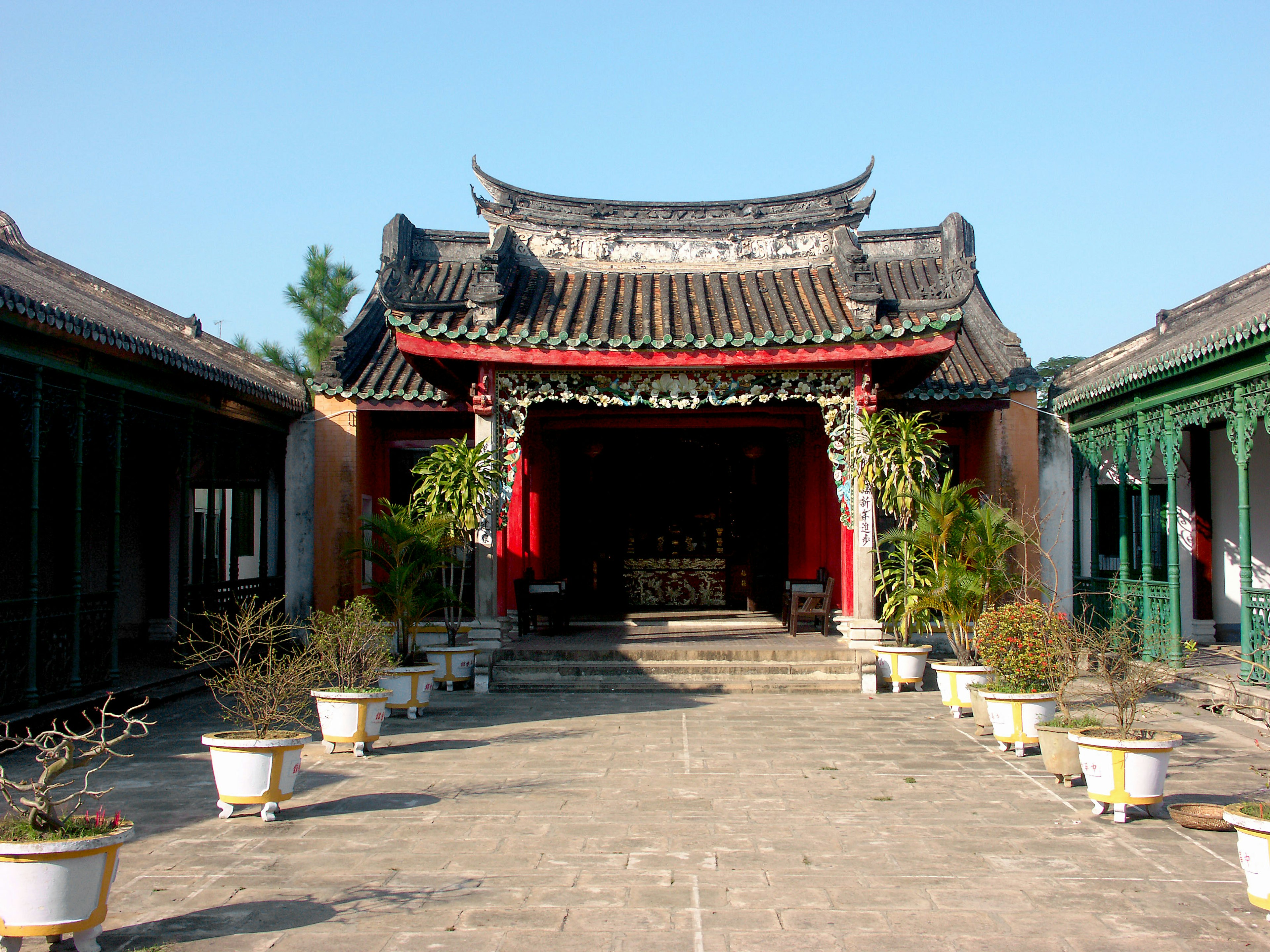 Vista de la entrada de un templo chino tradicional con techo decorativo y jardín circundante