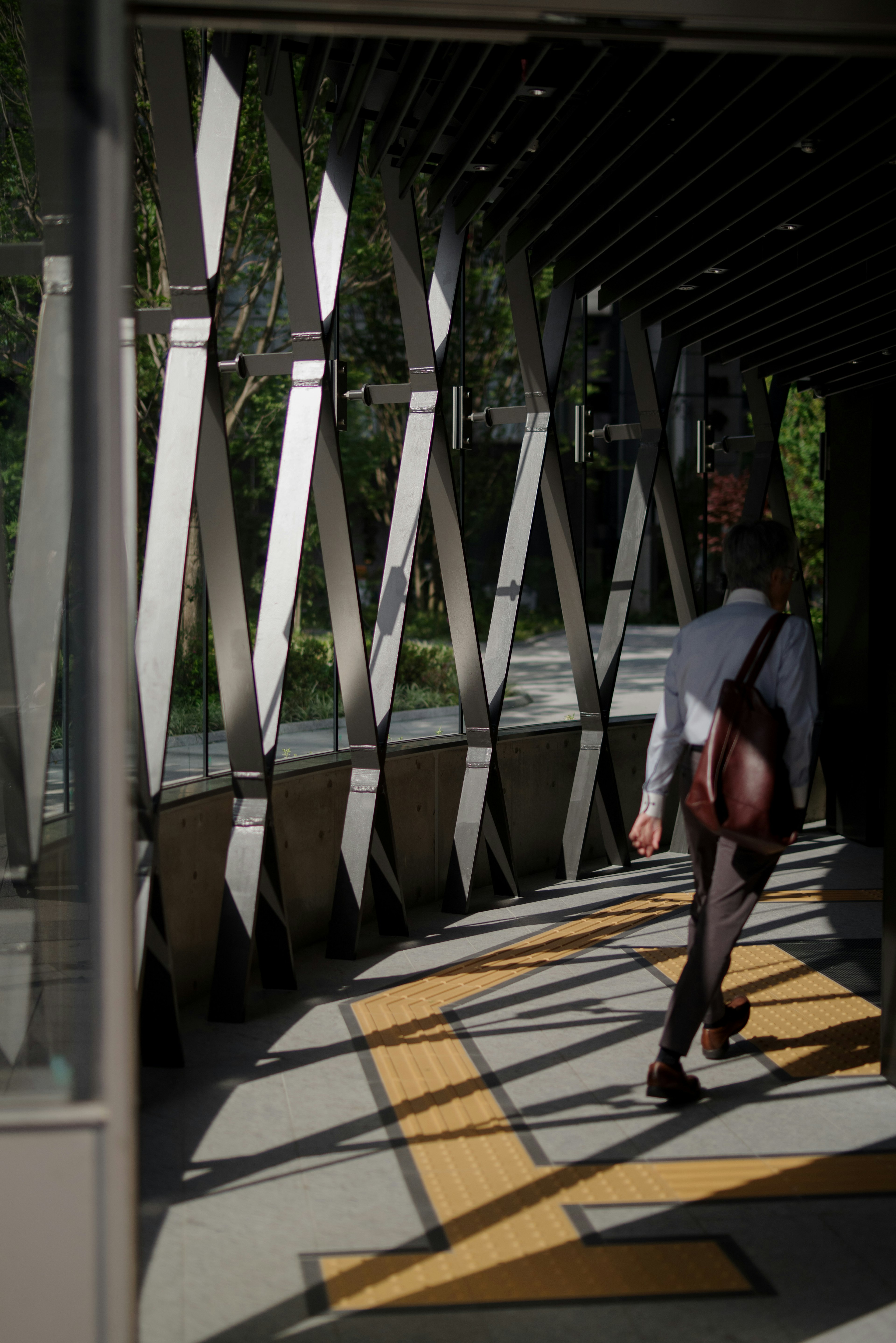 Businessman walking through a modern corridor with striking light and shadow contrasts