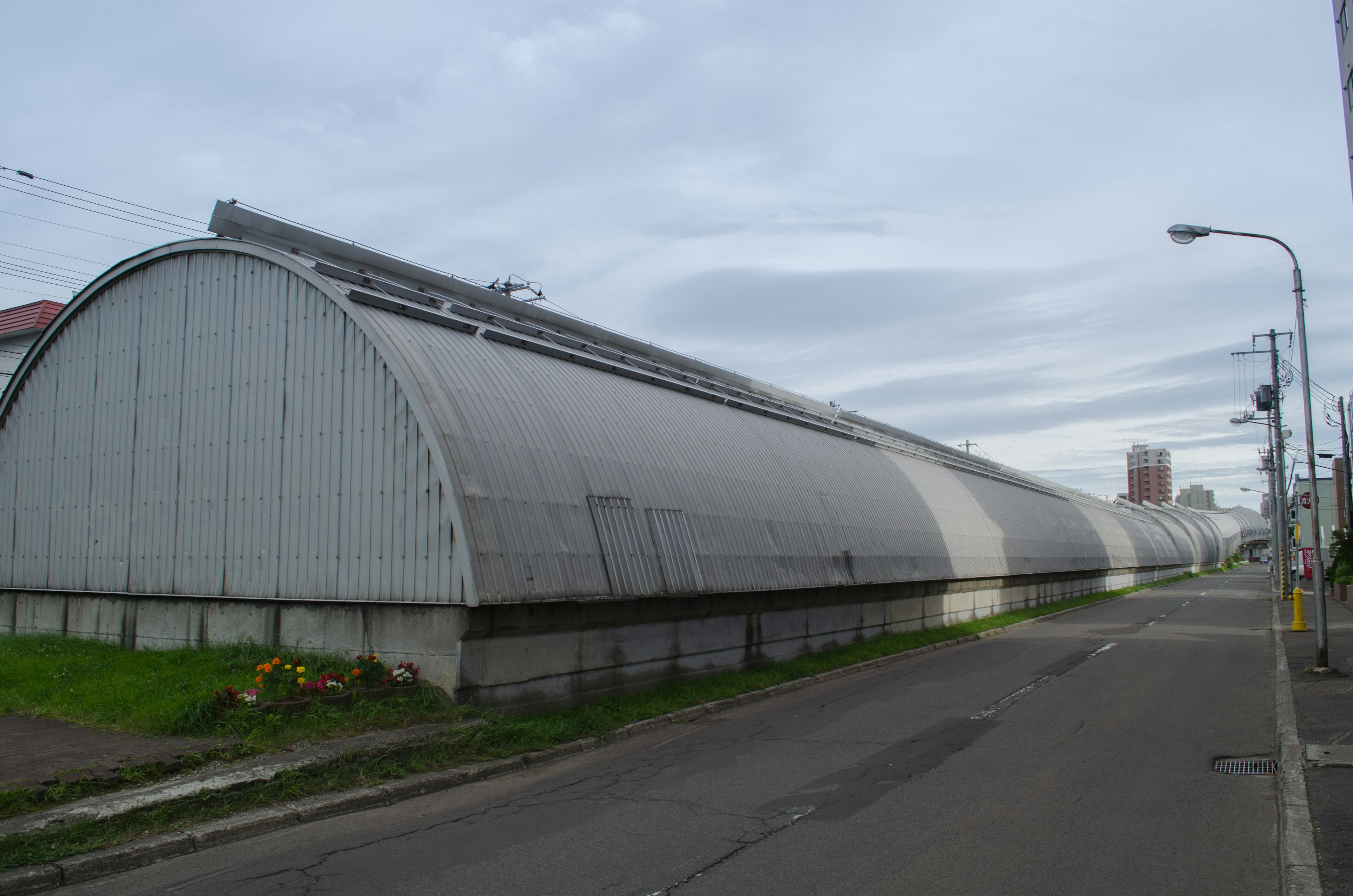 Langes, bogenförmiges Metallgebäude entlang der Straße