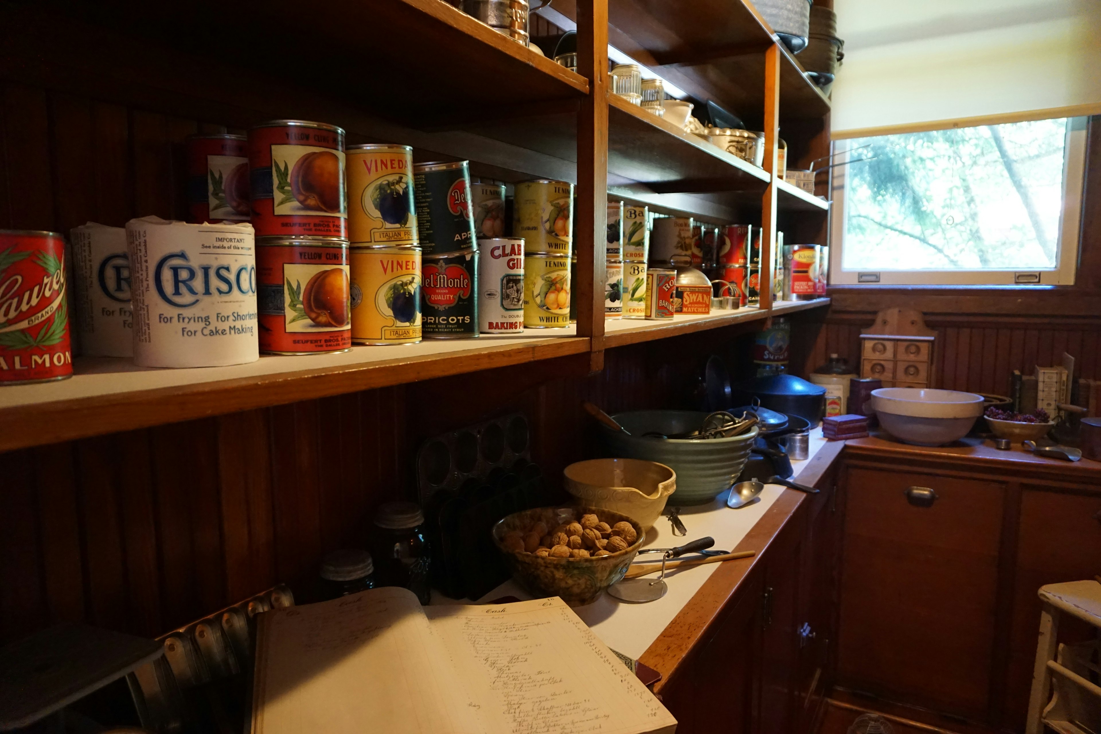 Corner of a kitchen with canned goods on wooden shelves